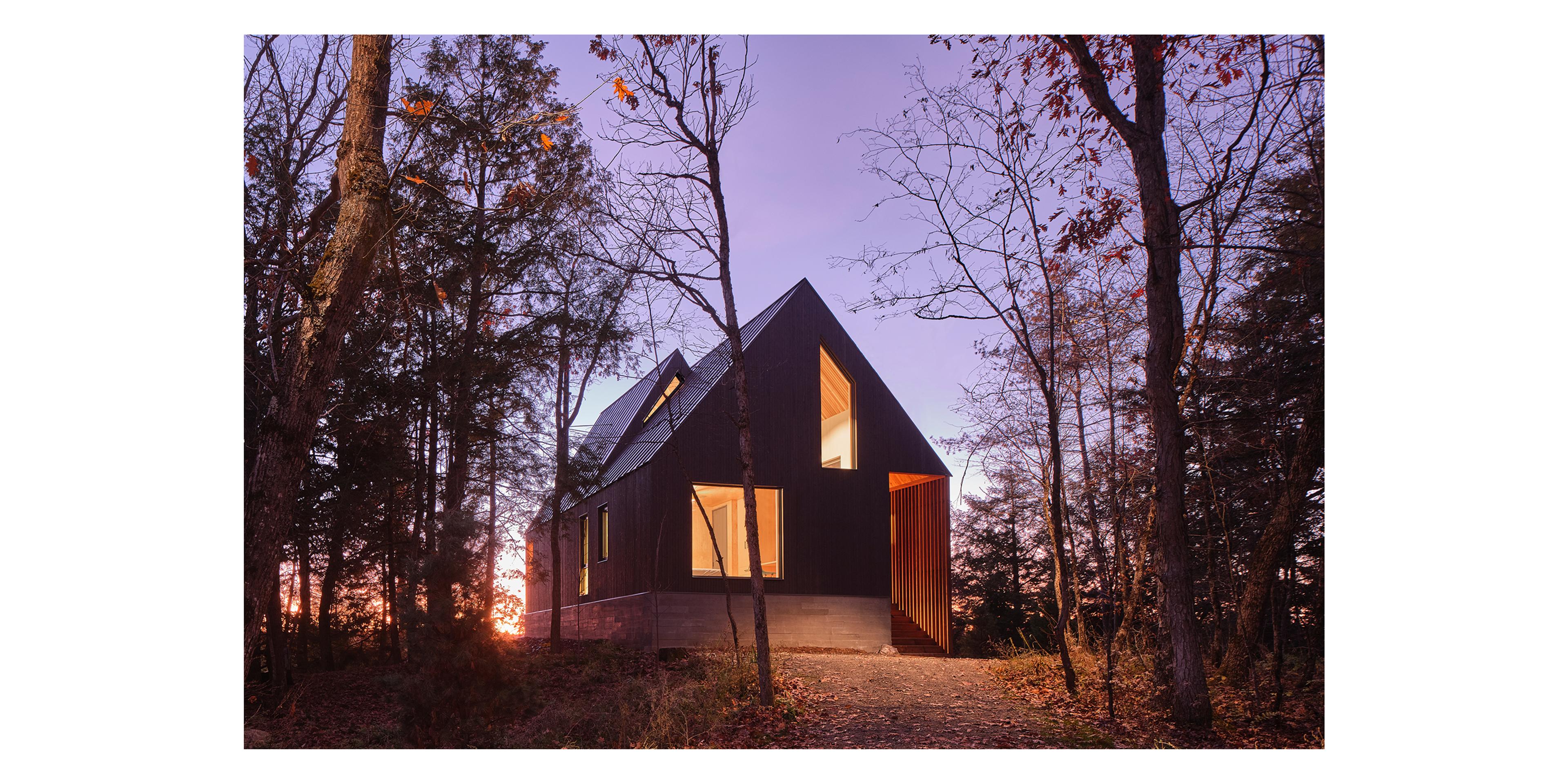 A-frame house with a purple sunset behind it.