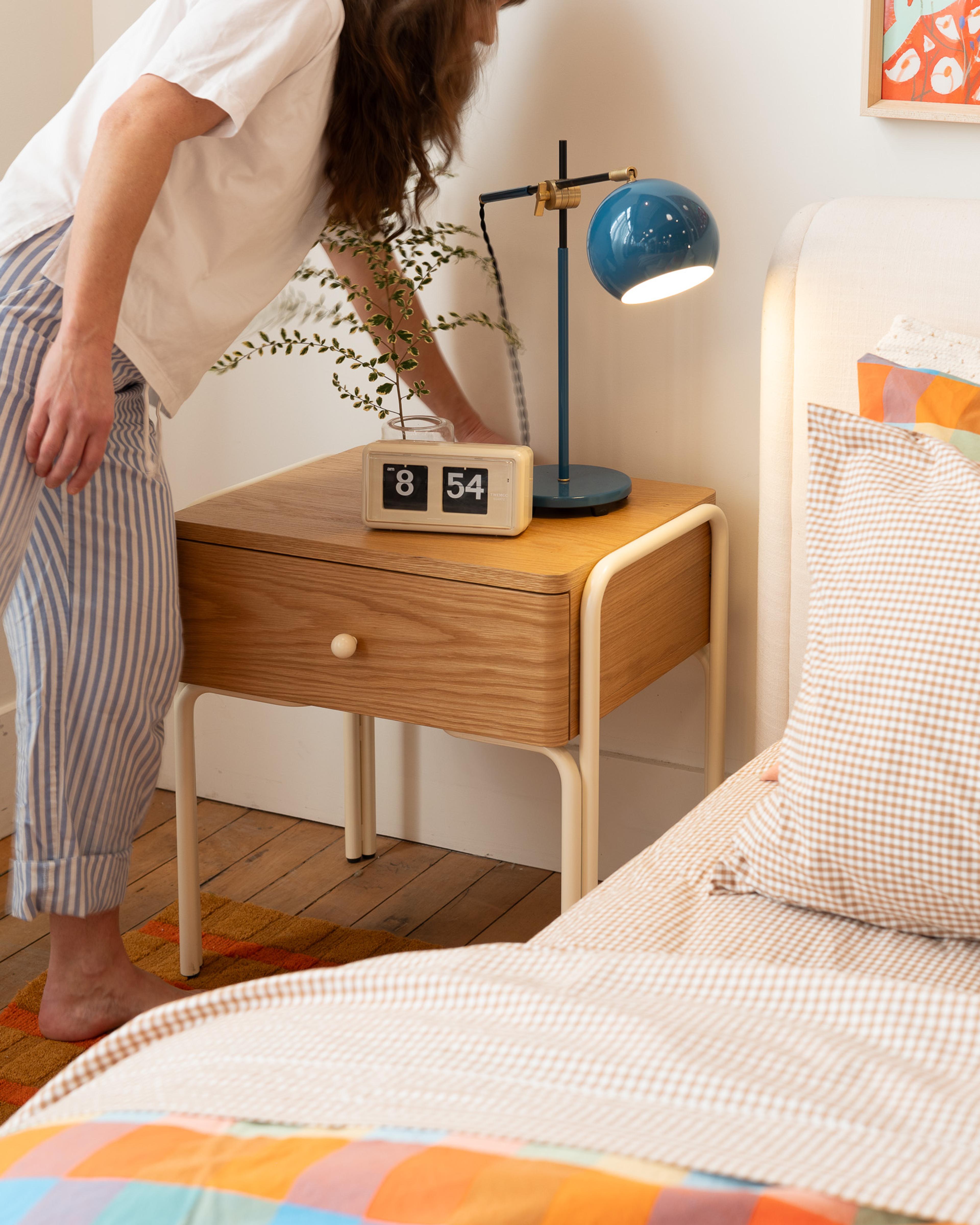 Person next to nightstand to turn on lamp. 
