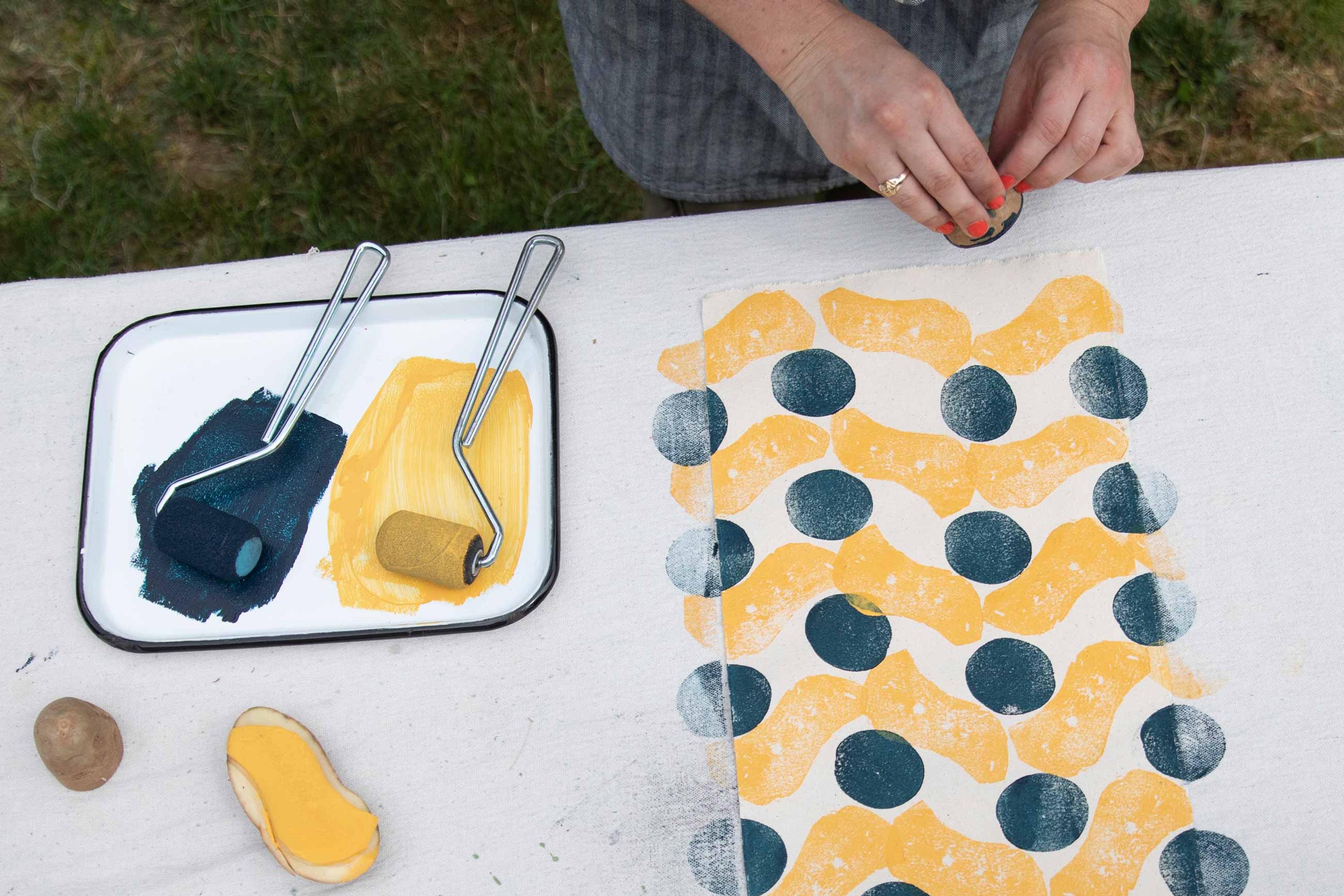 Woman making a block print out of homemade potato stamps.