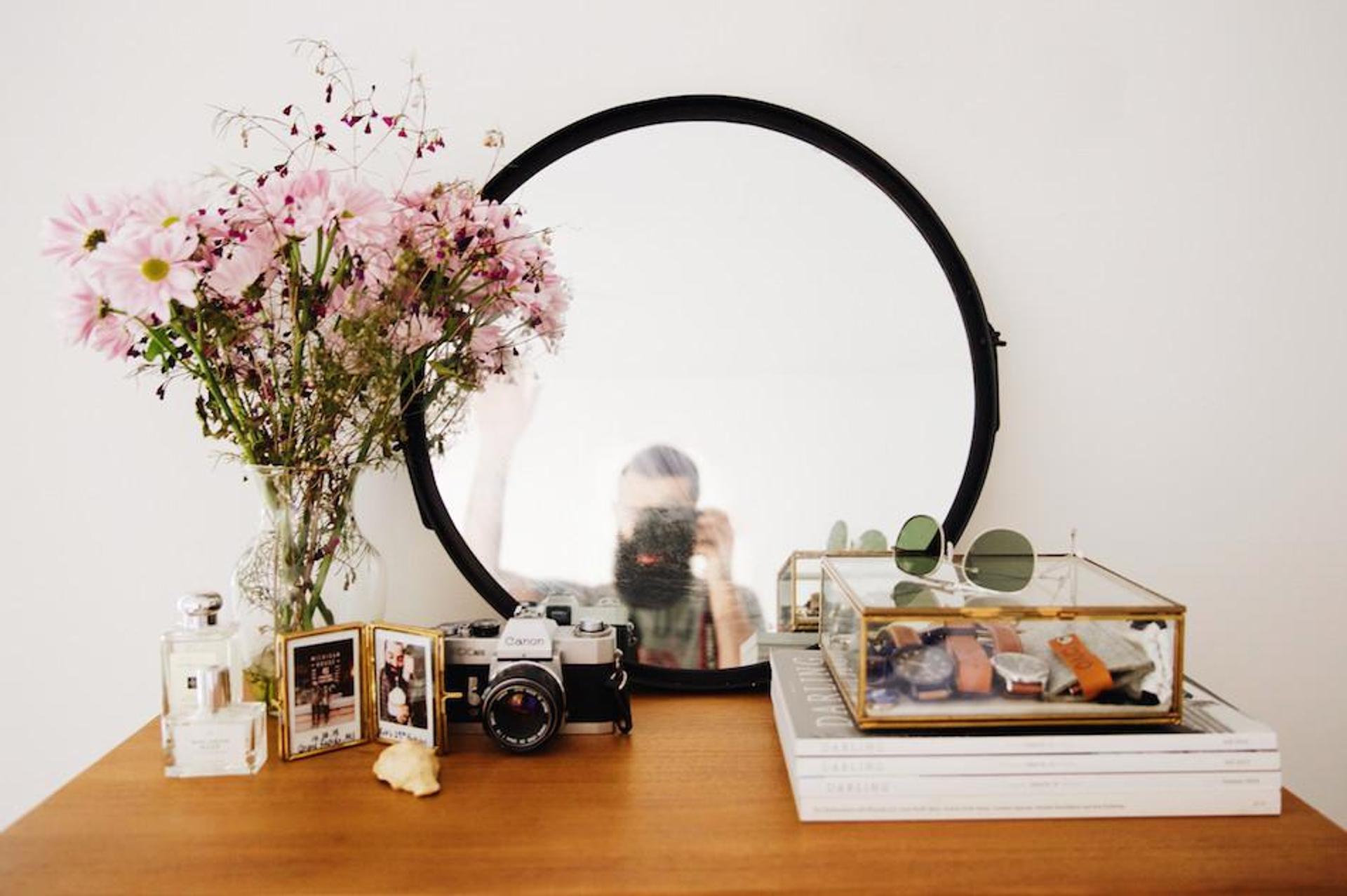 desk with a mirror and a vase with pink flowers