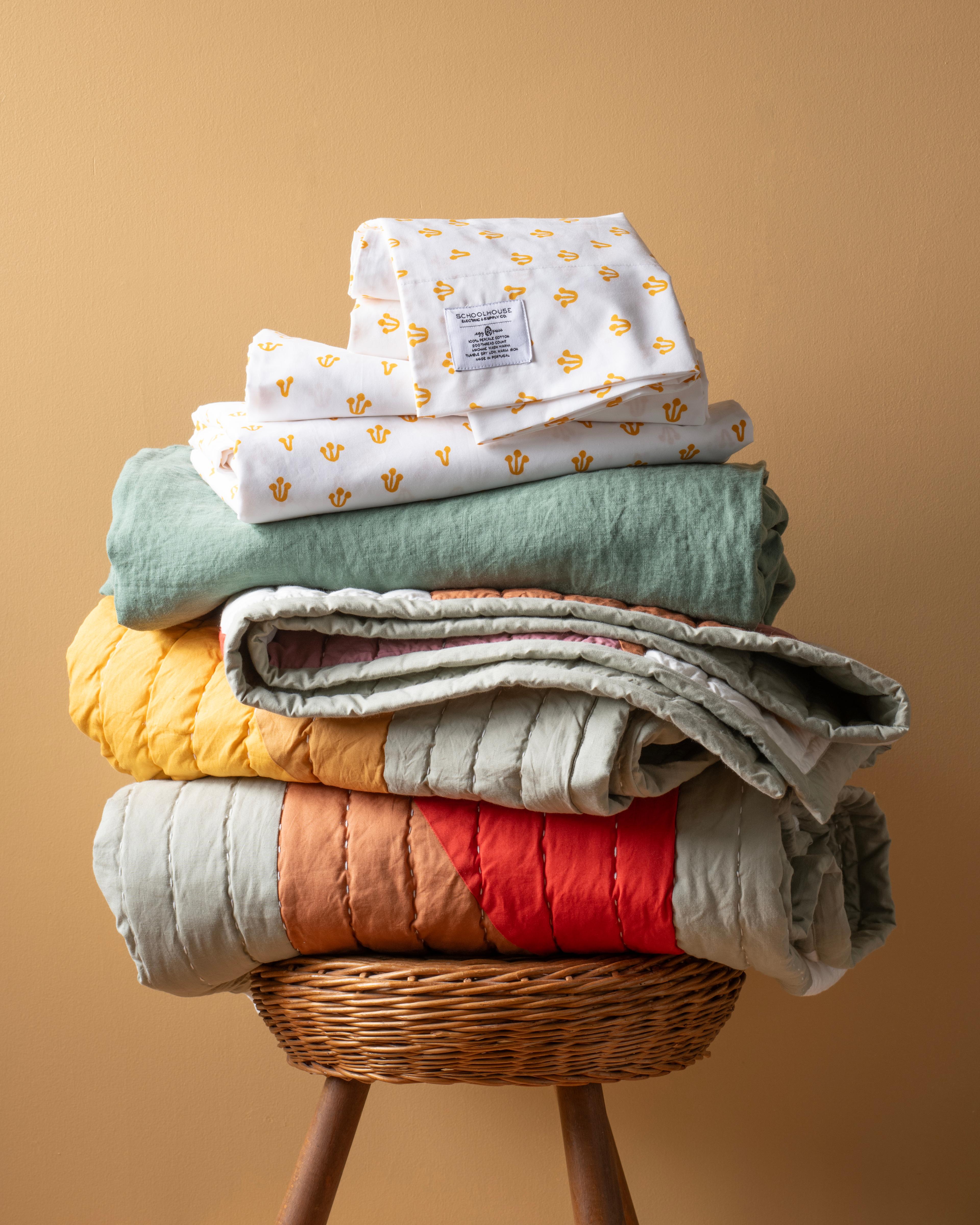 stack of bedding with sheets and quilts