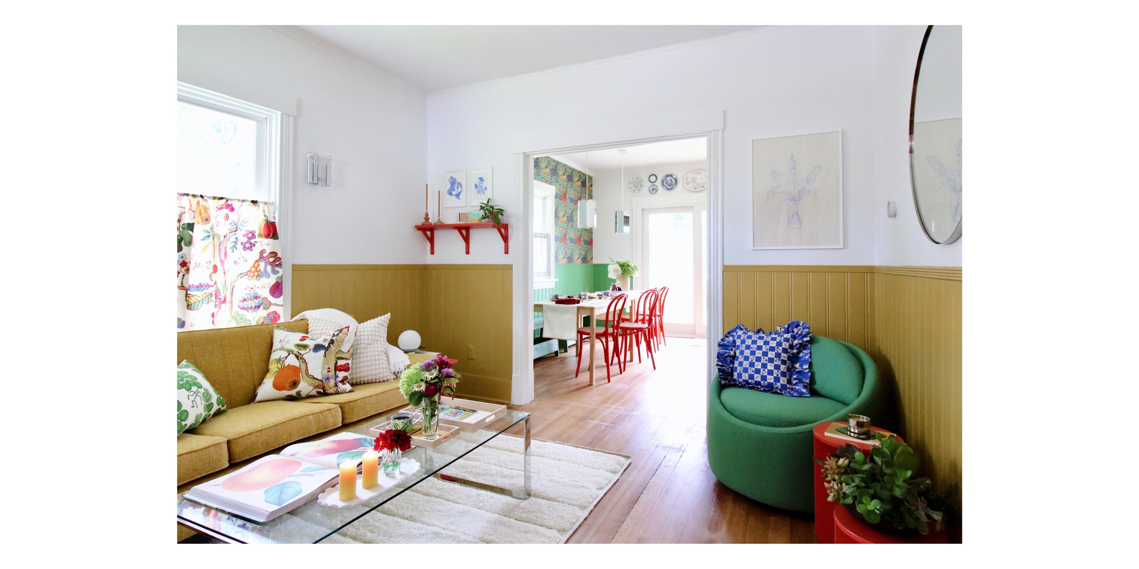 color filled living room looking into wallpapered dining room with red caned chairs