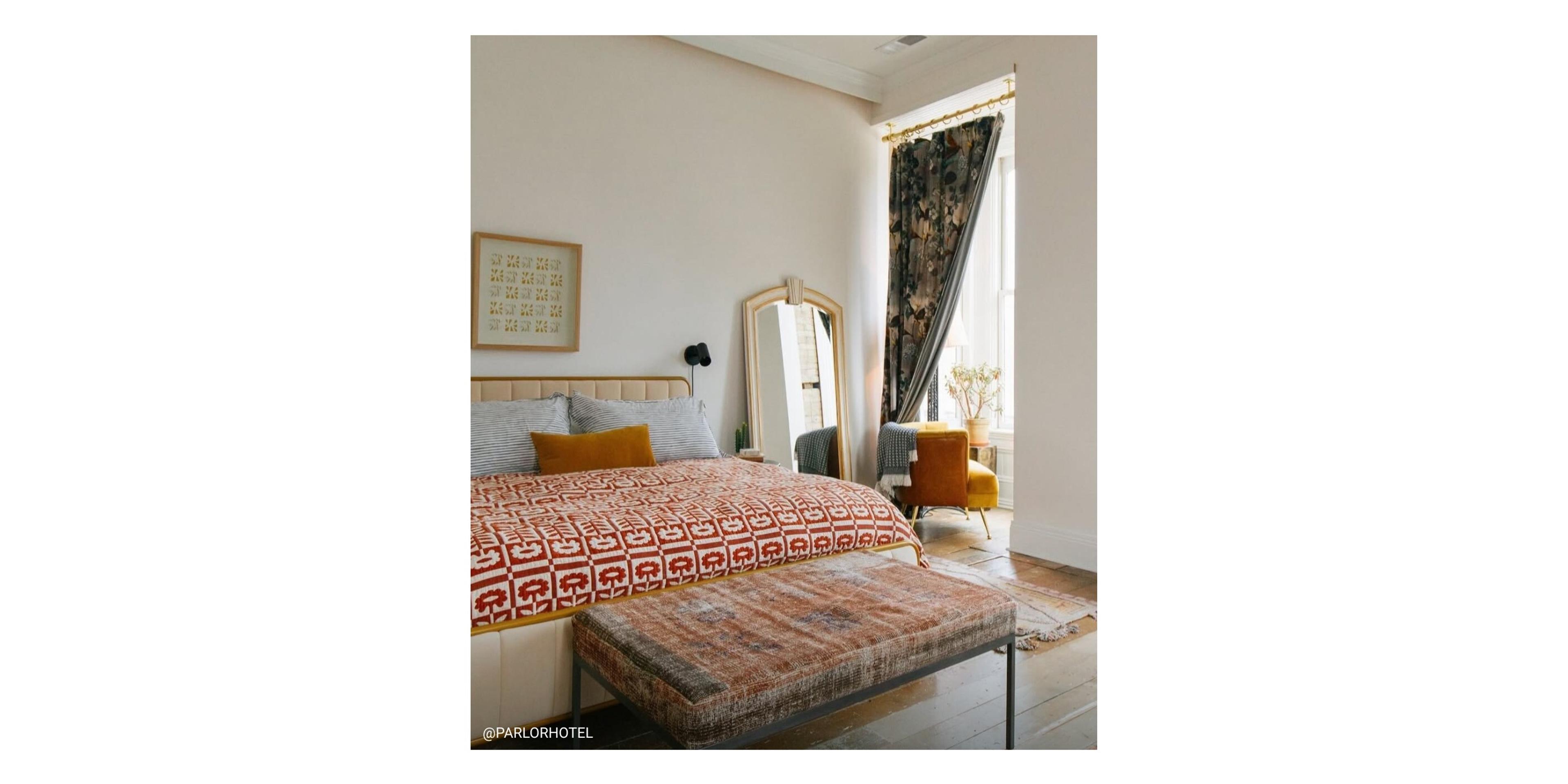 Large white bedroom with floral quilt on bed. 