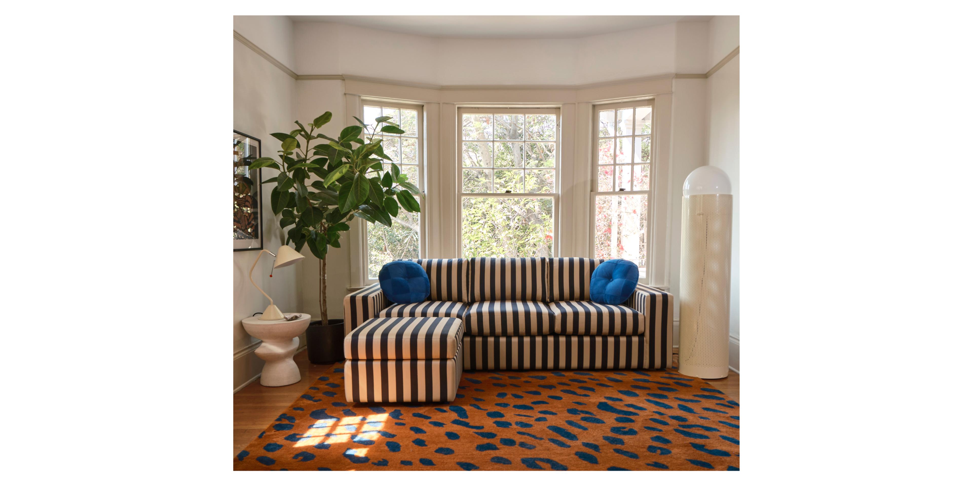 living room with striped sofa and ottoman 