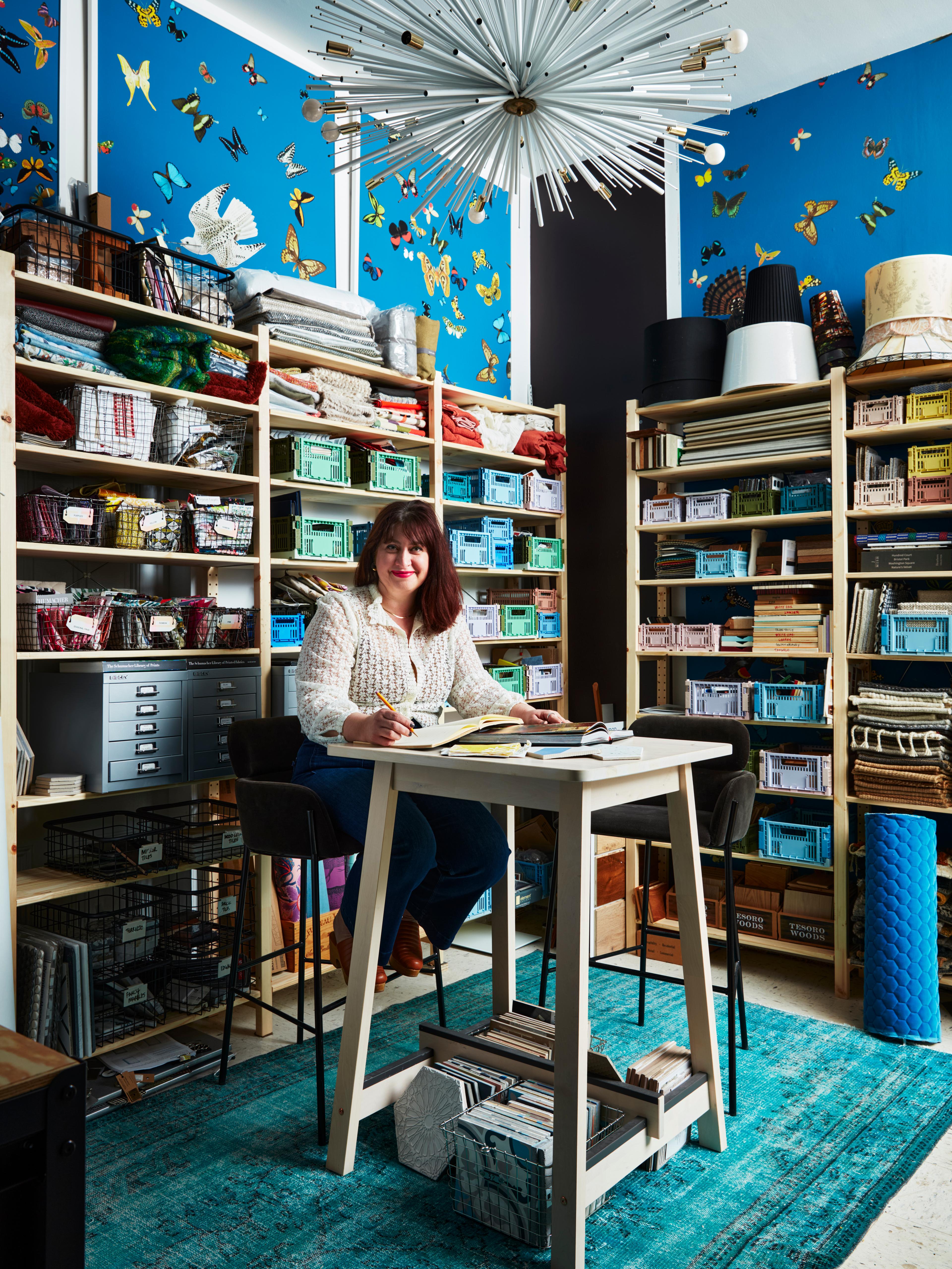 Woman sitting behind a desk in an eclectic room.
