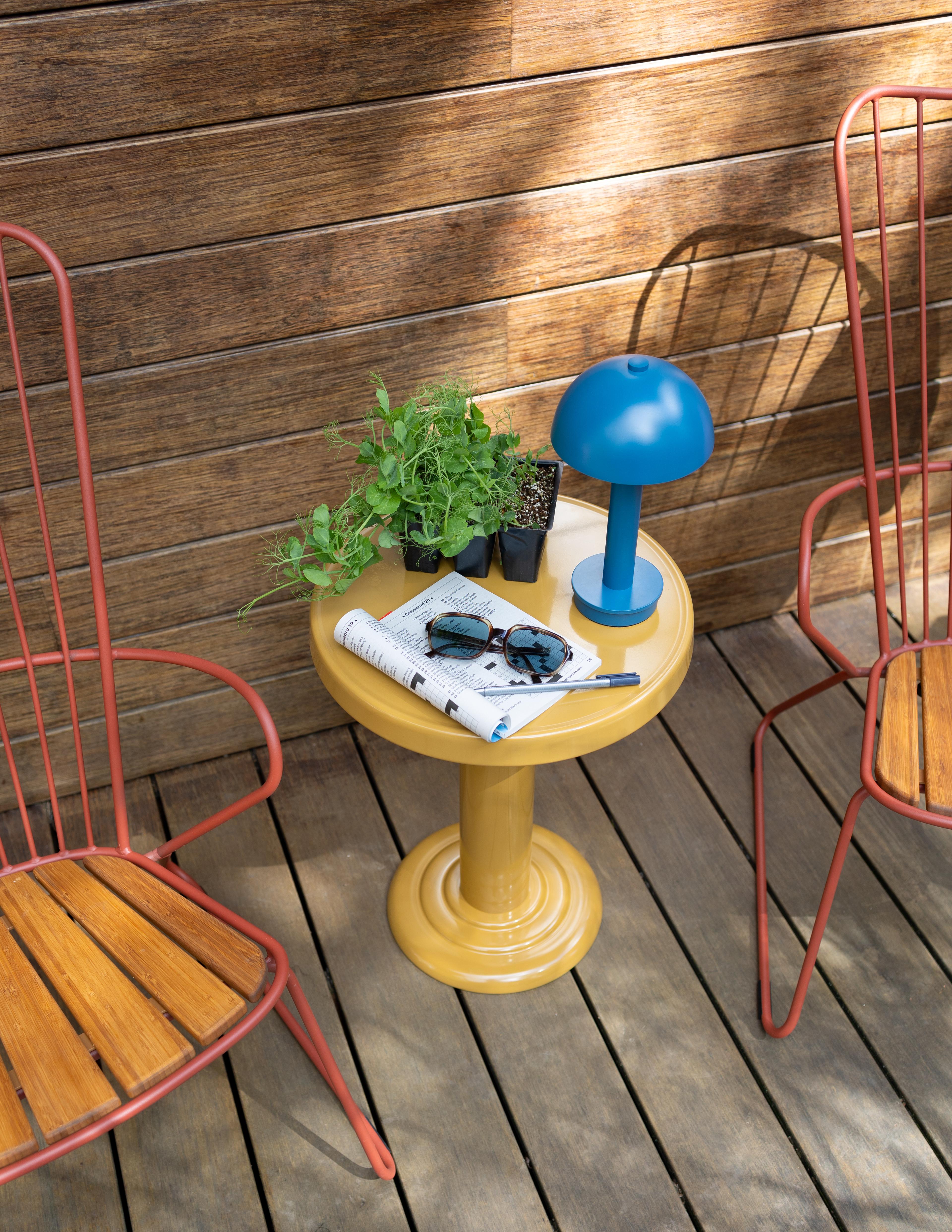 Portable lamp on outdoor table with sunglasses next to it 