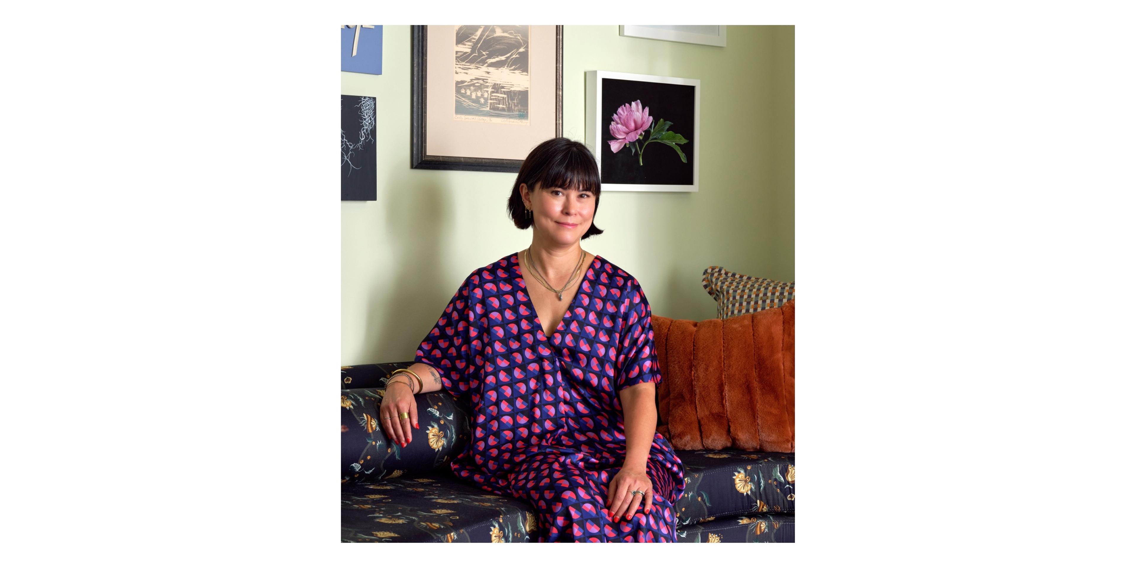 Woman sitting on a sofa with a green wall behind her.