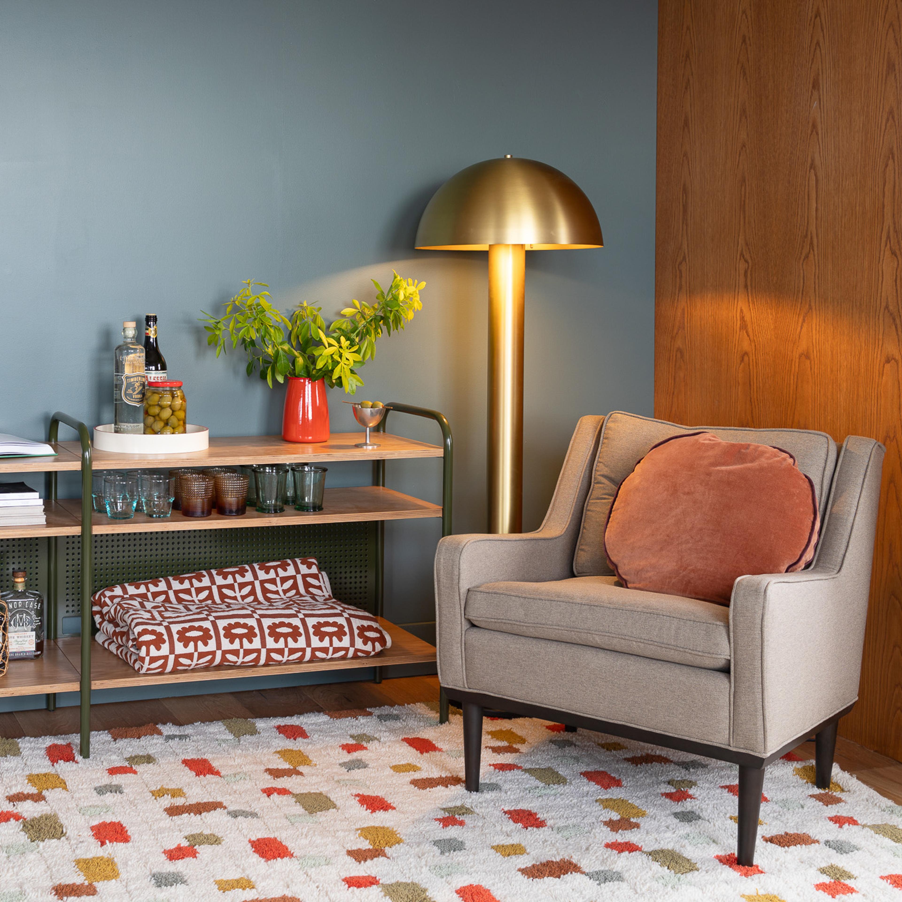 Living room corner with gray flannel chair and natural brass lamp illuminating the corner 