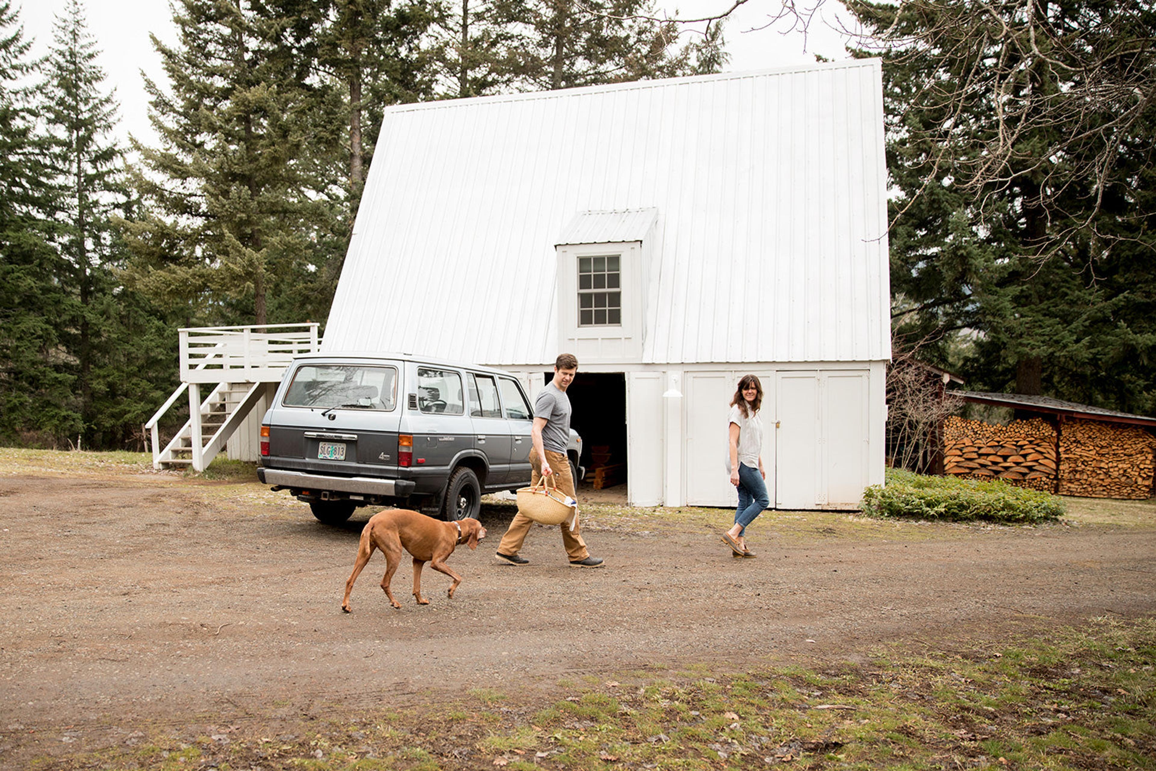 man and a woman walking a dog in a driveway