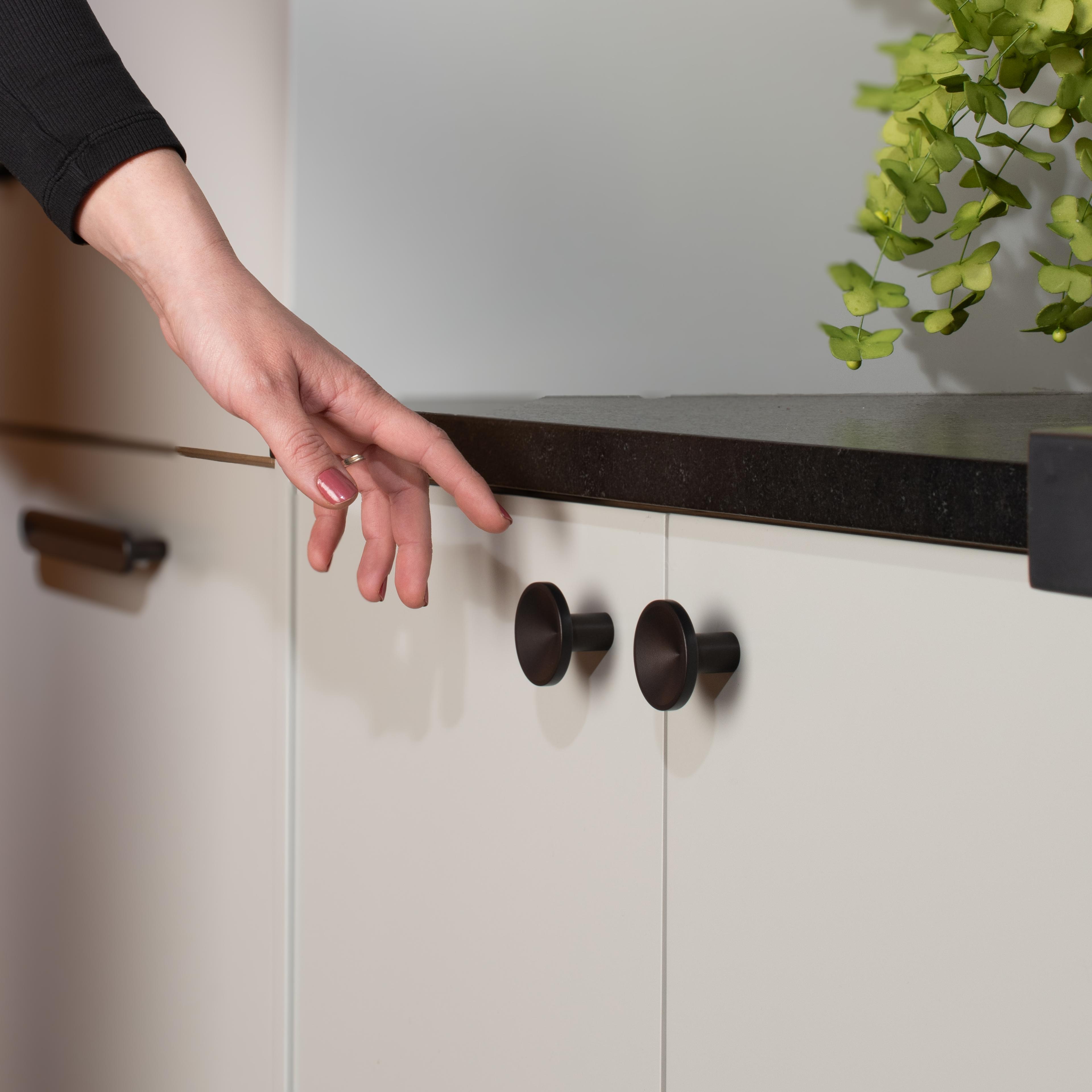 Person reaching to open cabinet.
