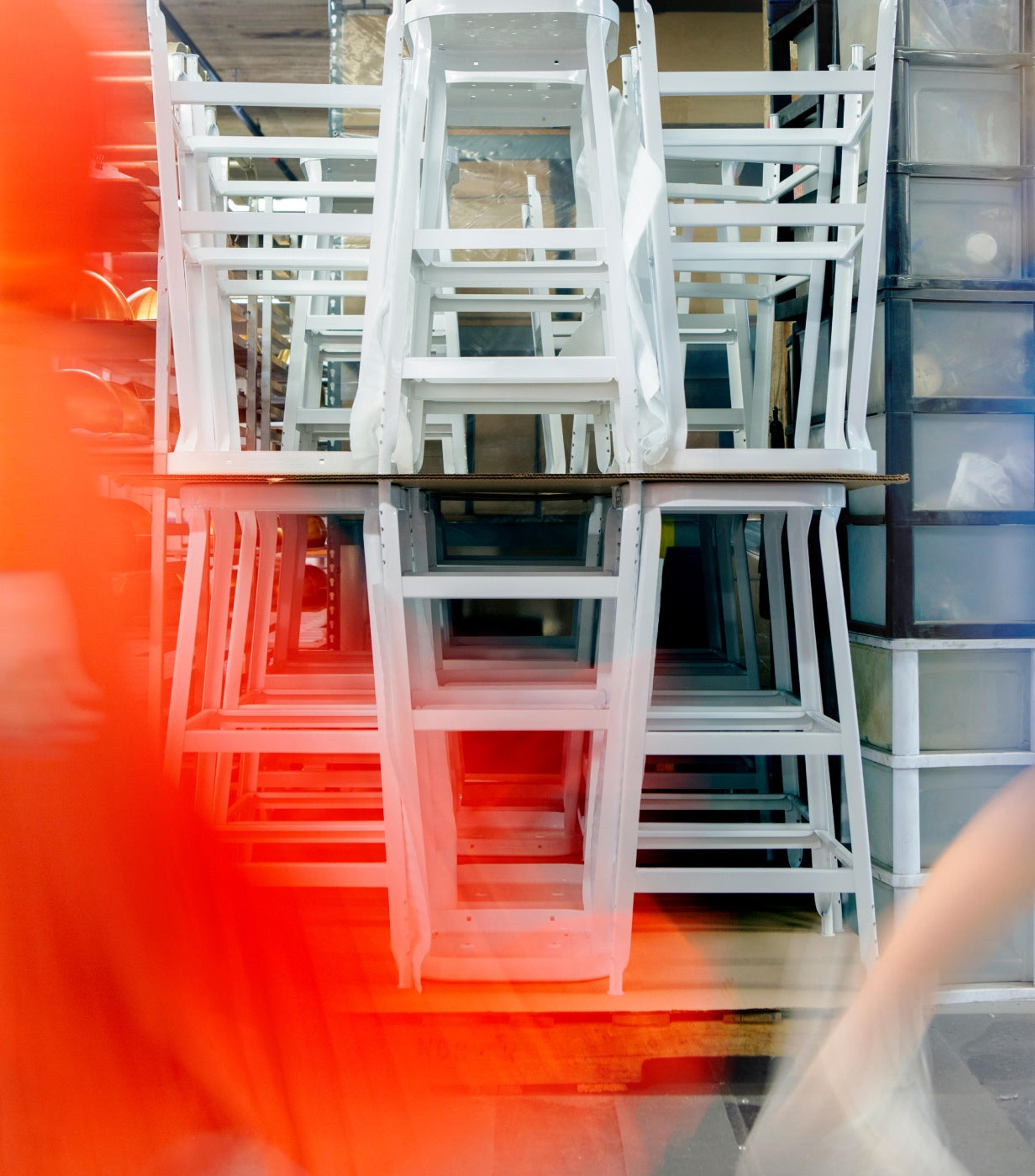 Artsy photo of white stools stacked on top of each other with red blur in front