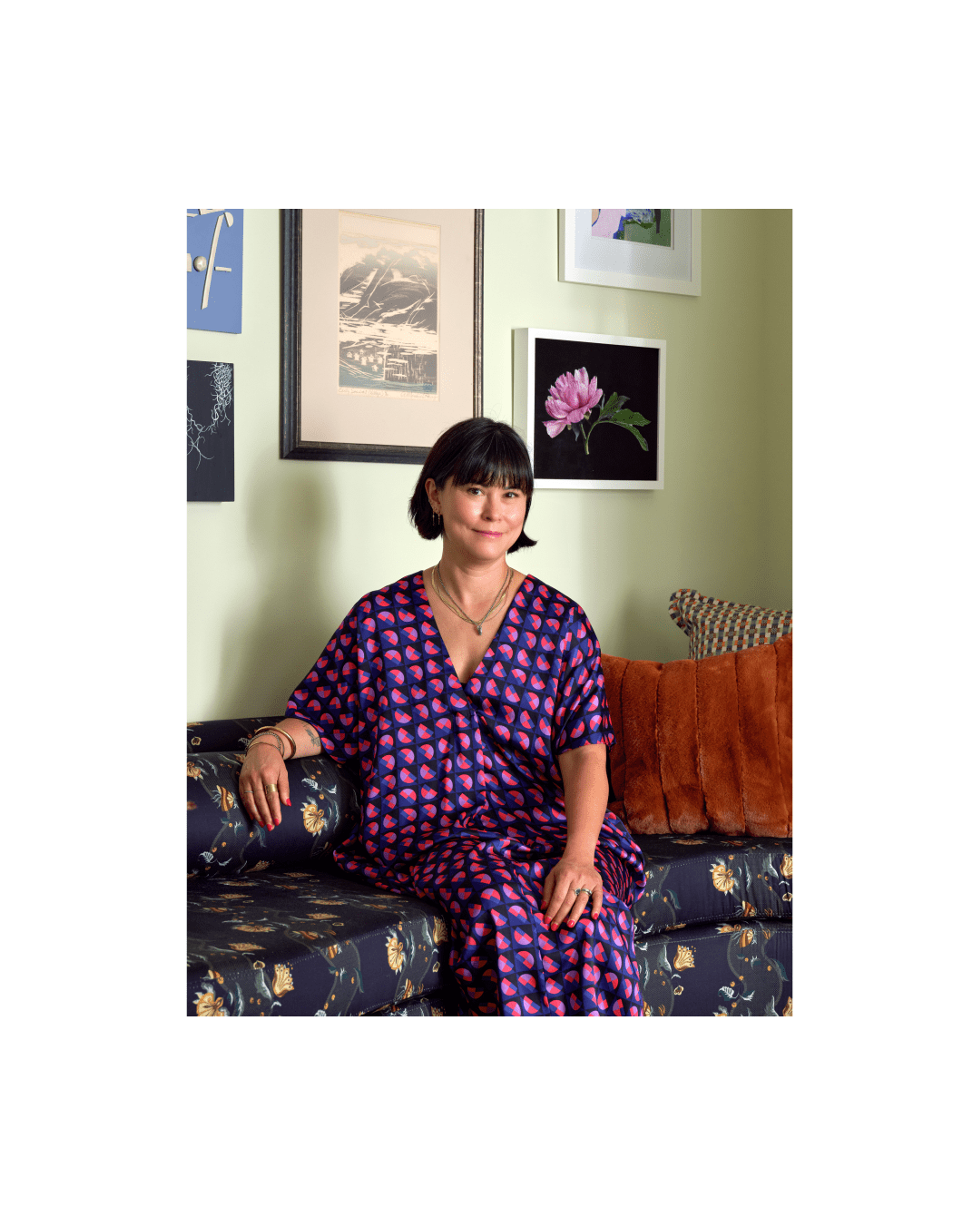 Woman sitting on a sofa with a green wall behind her.