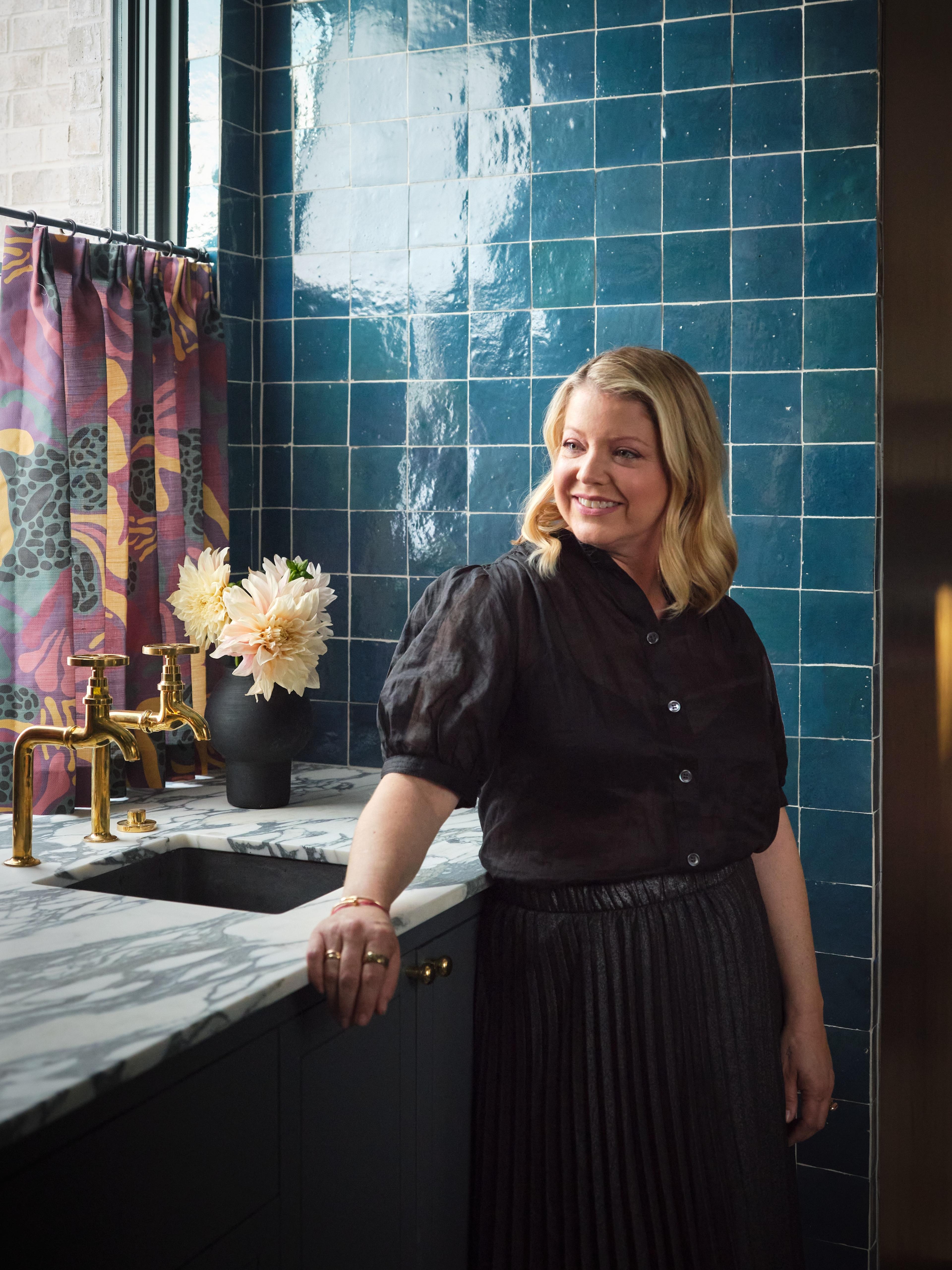 Blonde woman standing by a sink.