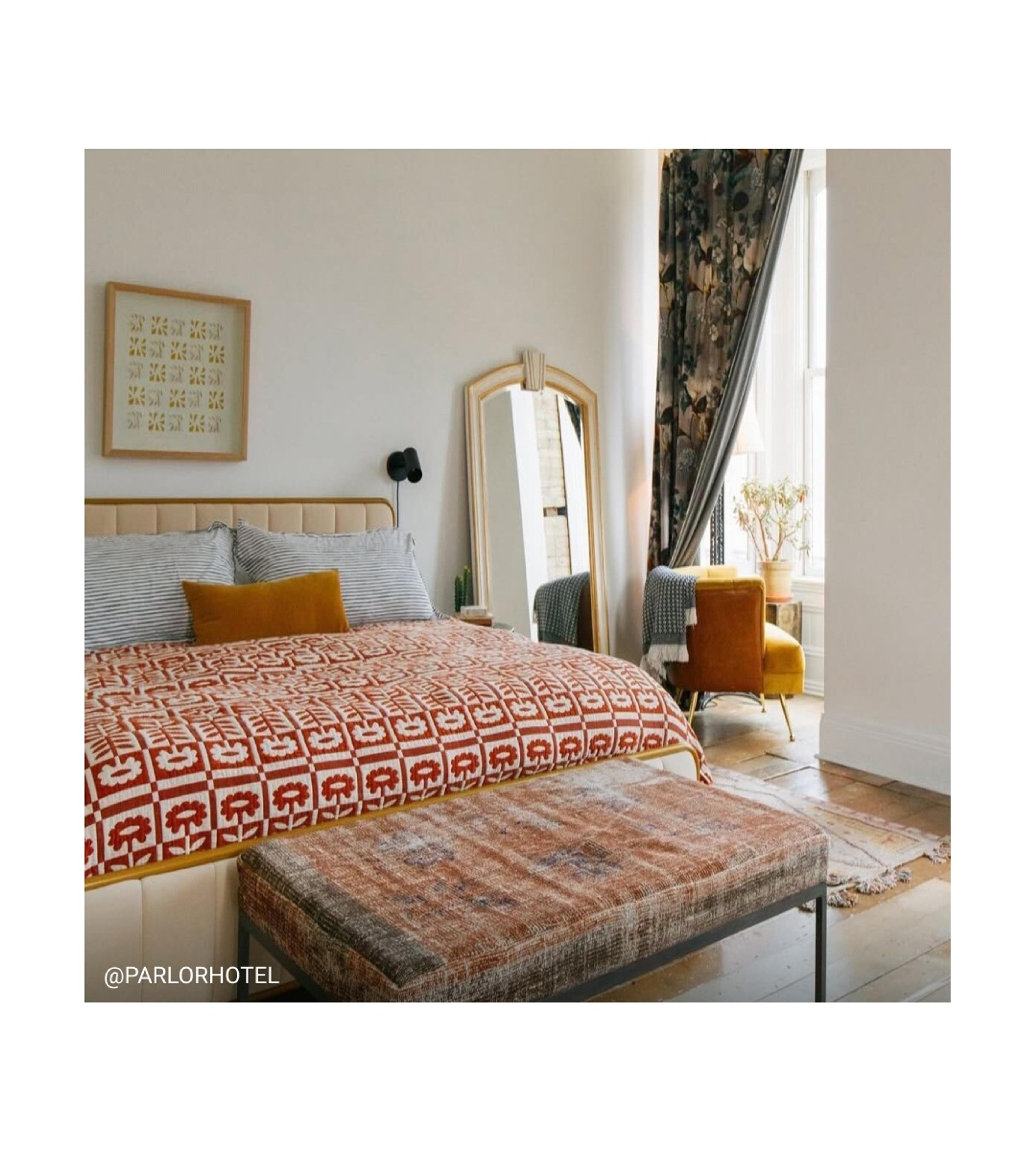 Large white bedroom with floral quilt on bed. 