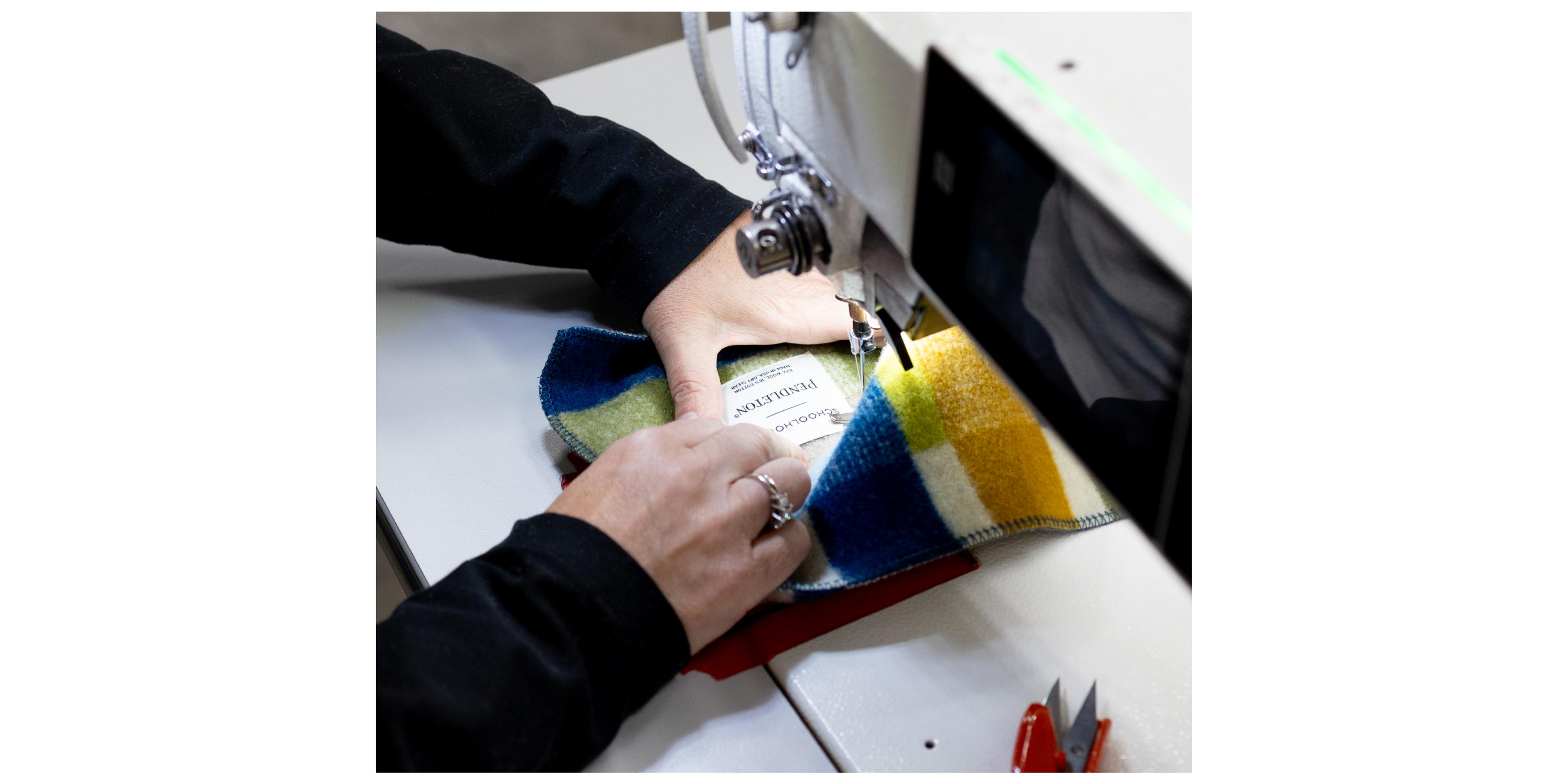 person sewing label onto wool blanket