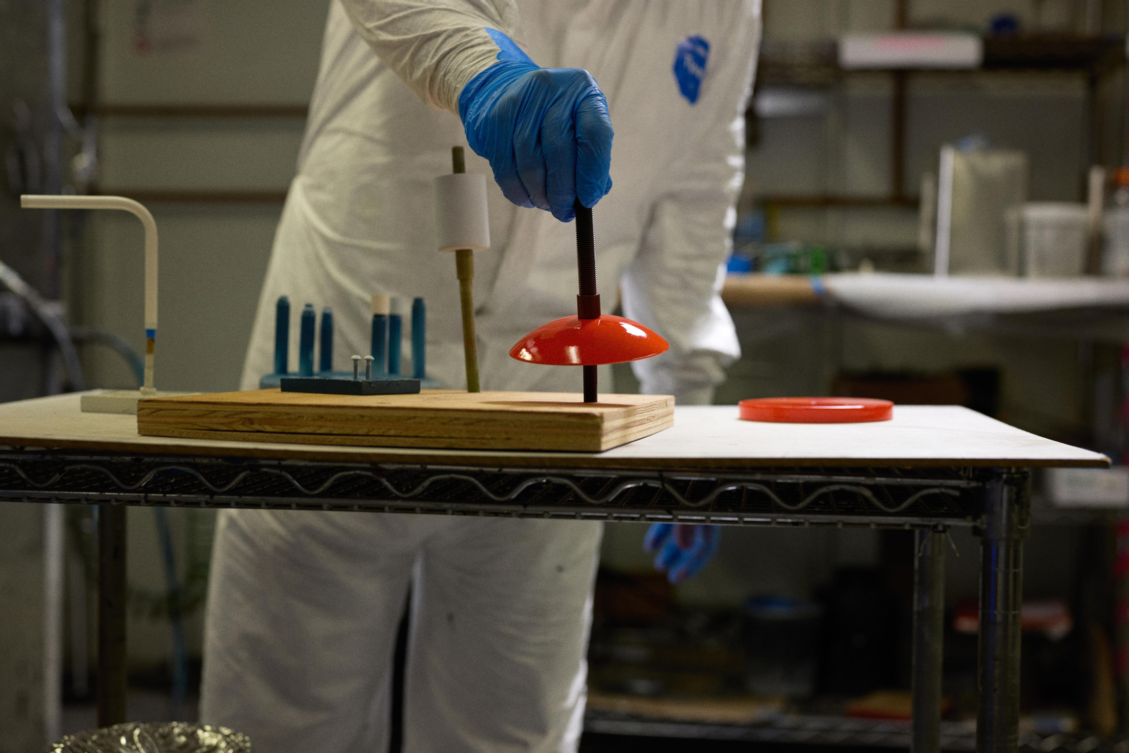 person placing wet light fixture piece after painting