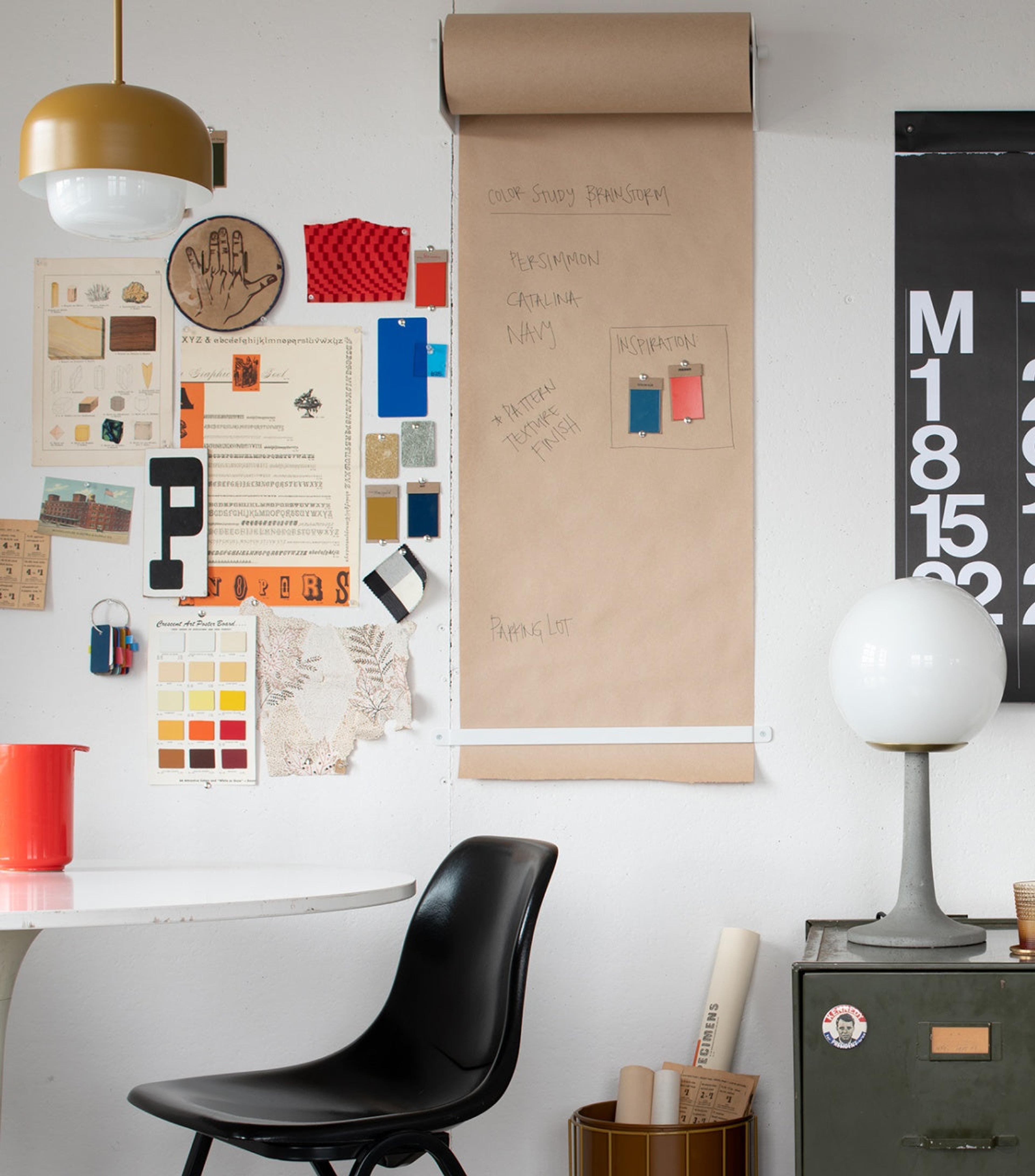 Wall covered in writing and post it notes, black chair and white table in foreground