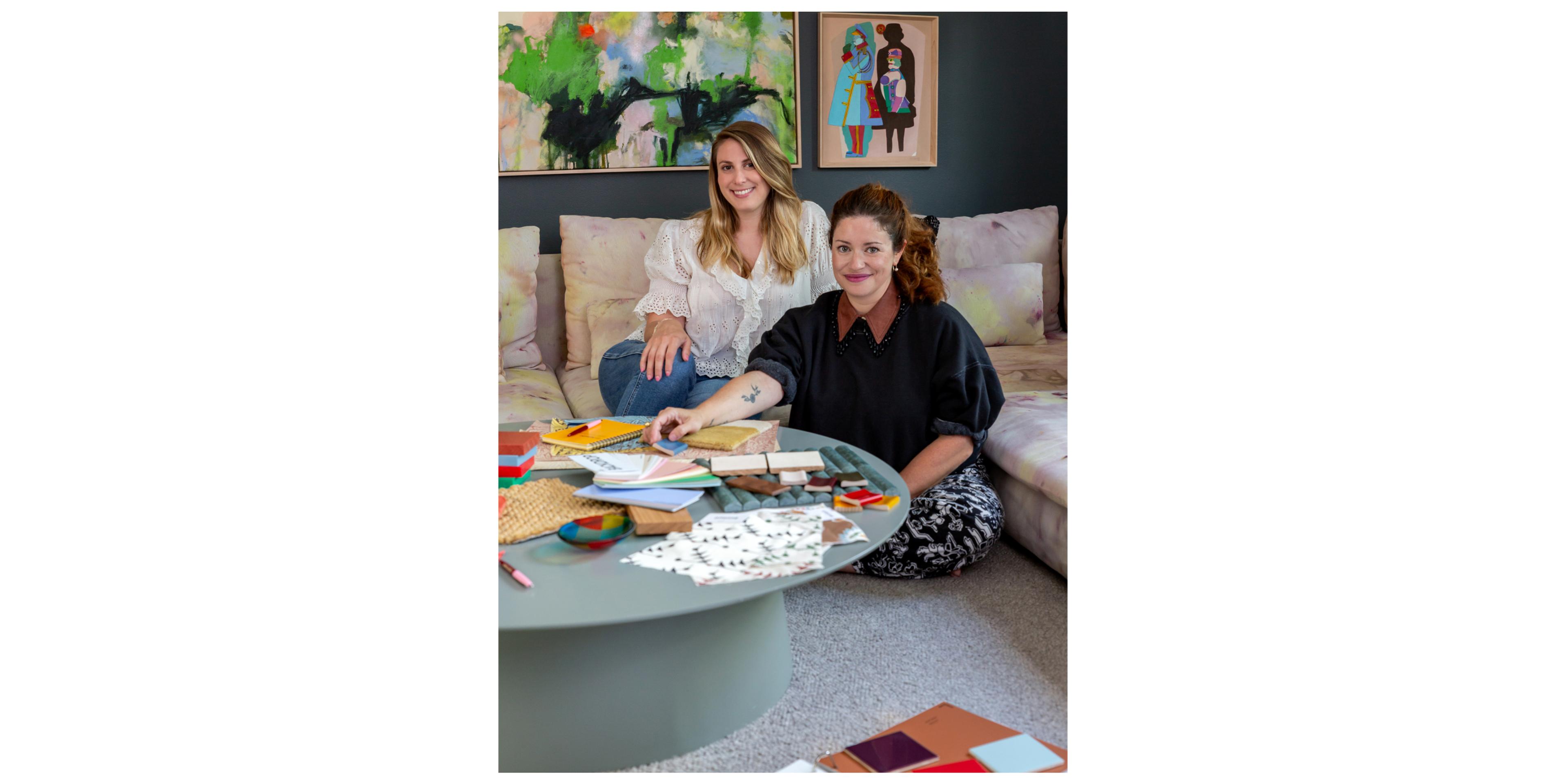 Portrait of designers witting on couch with creative materials laid out on table