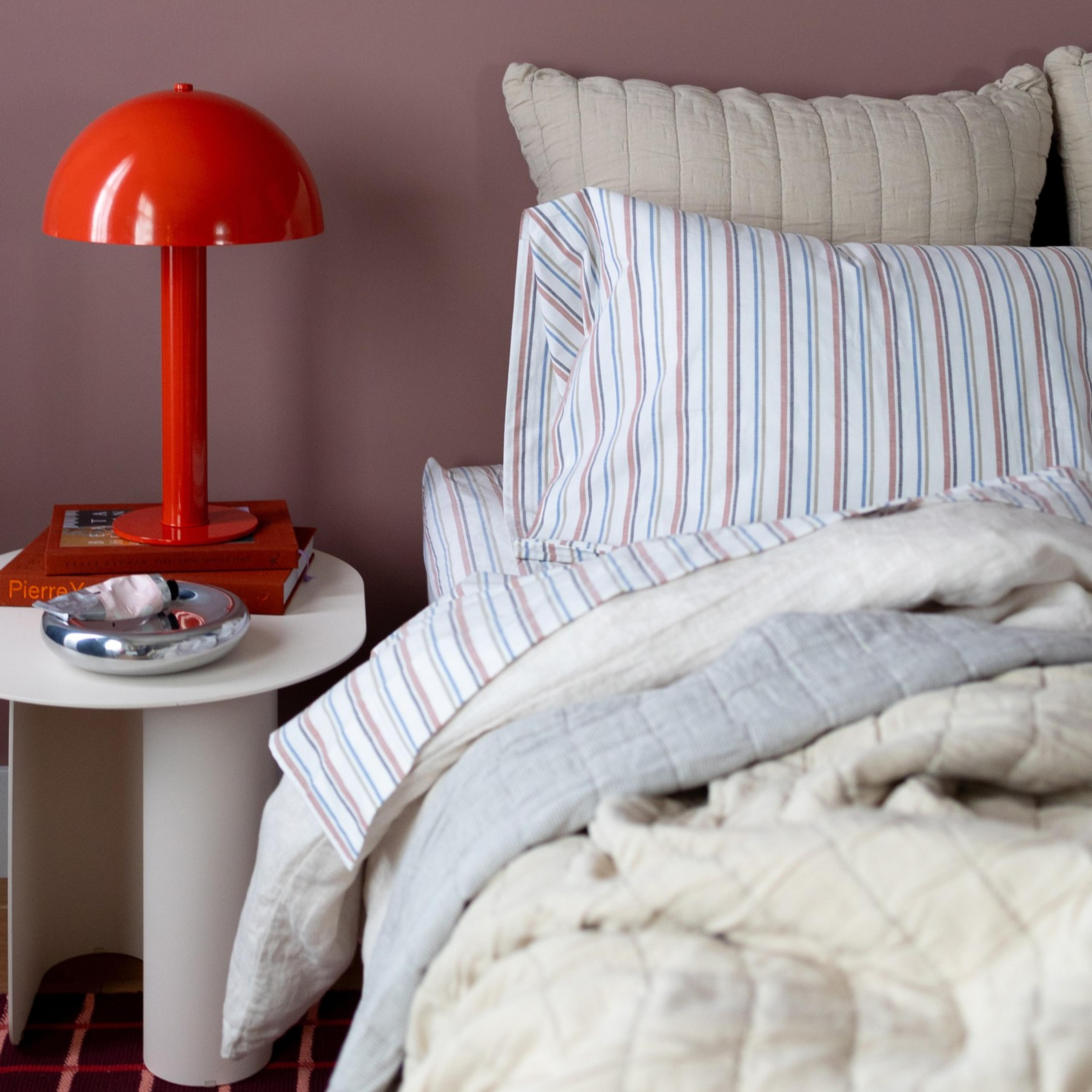 red lamp next to white bed 