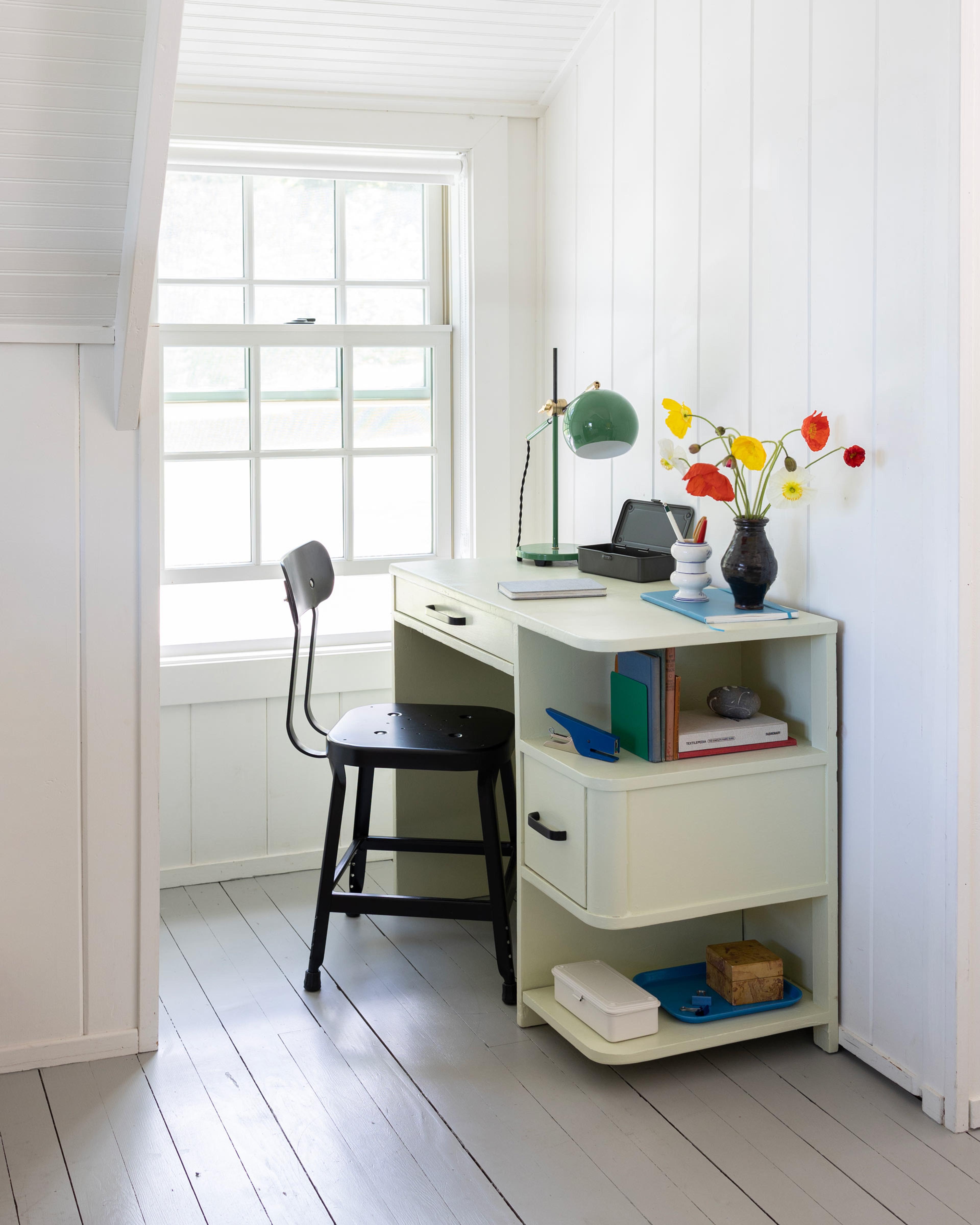 desk nook with green table lamp and wildflowers 