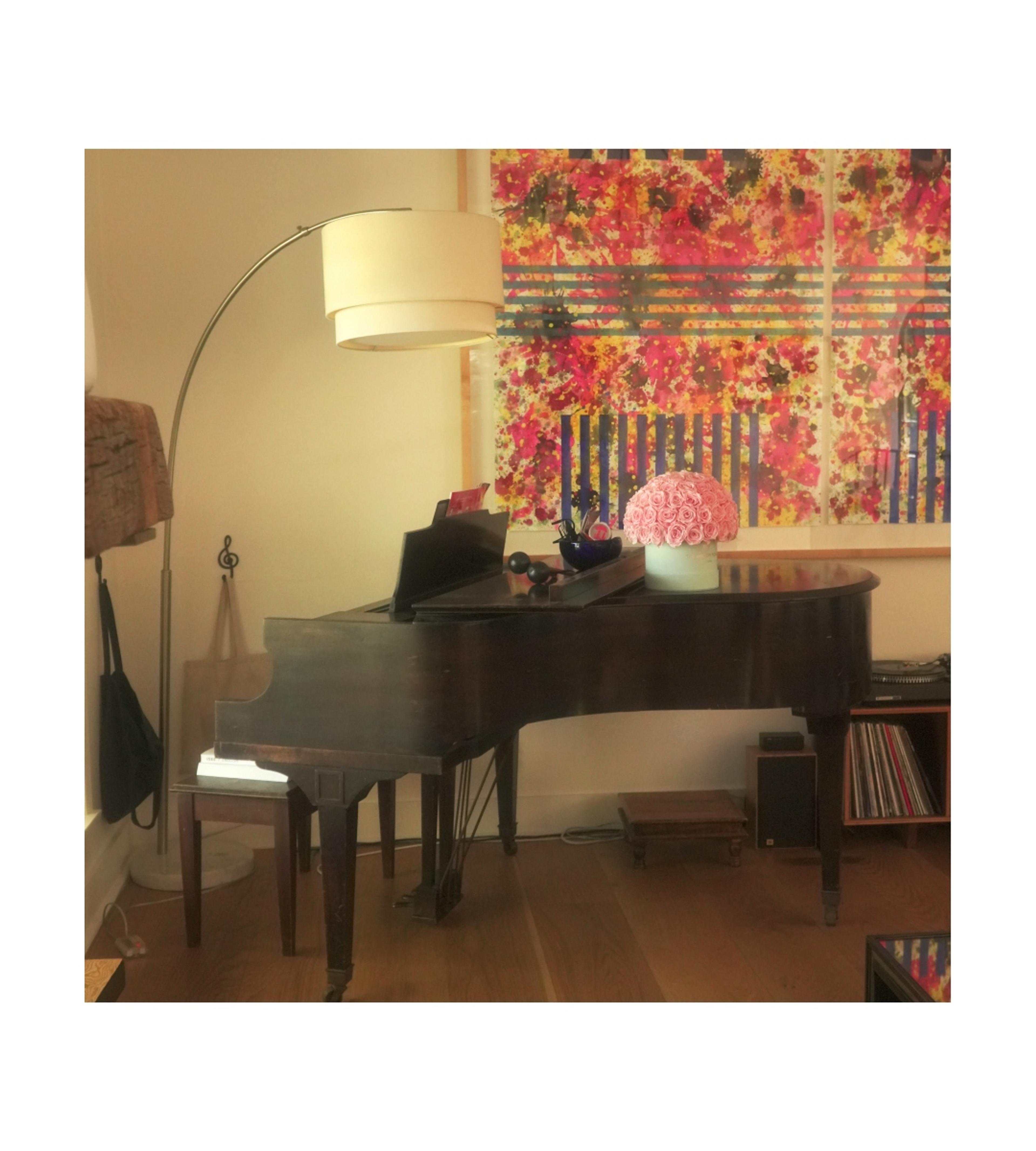 piano in corner of room with lamp over hanging 