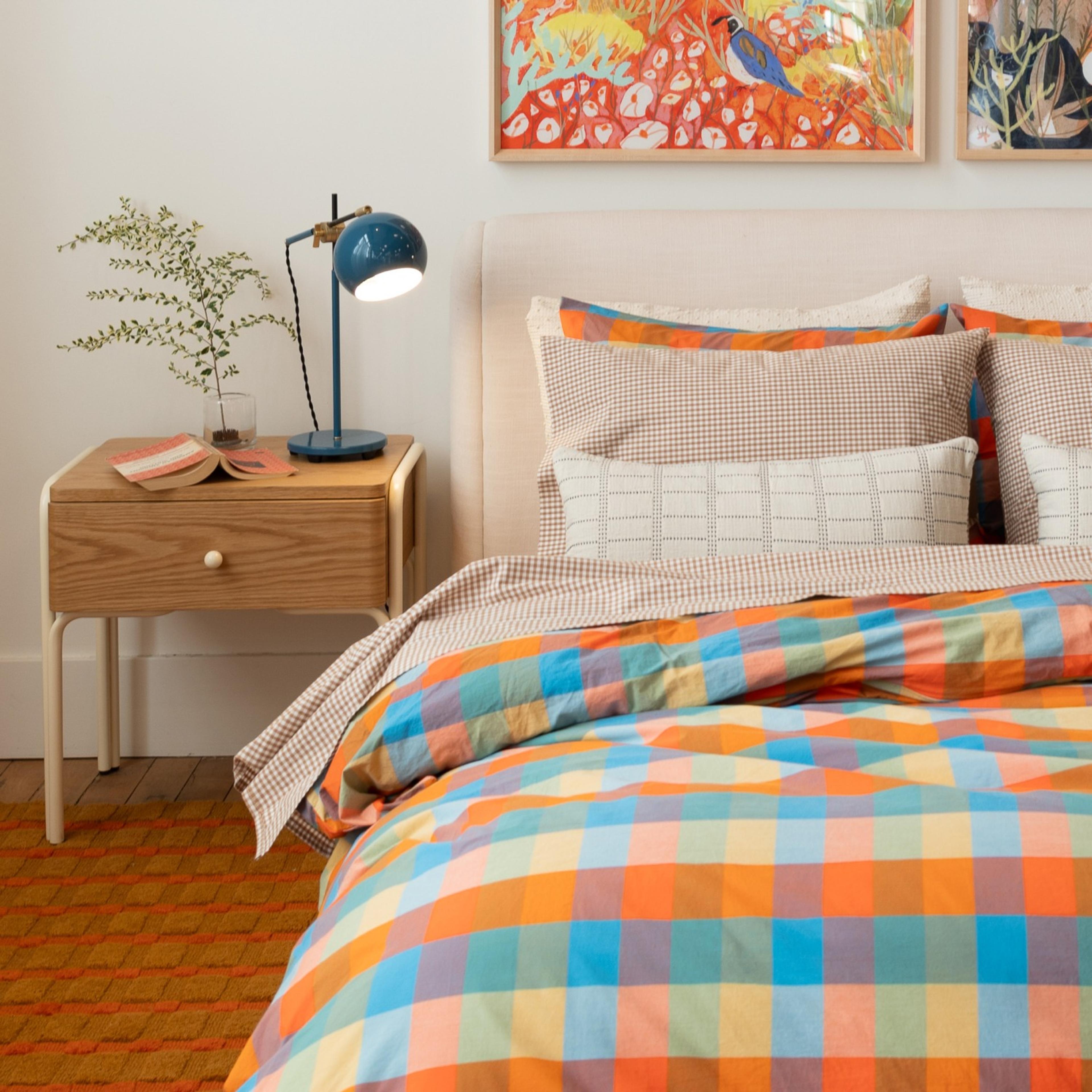 bright yellow, orange, and blue checkered duvet on bed