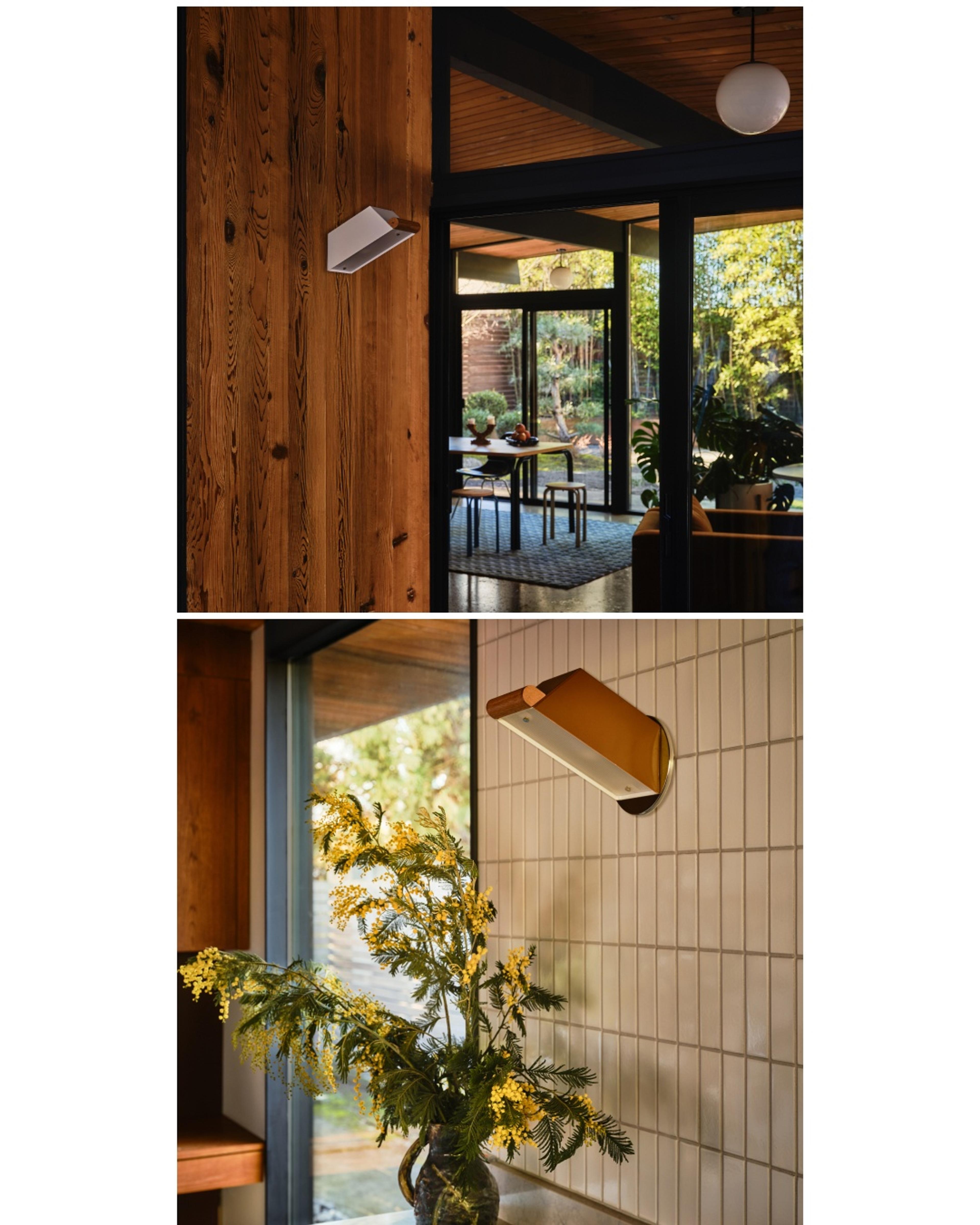 Sconce on wooden wall in entryway and another sconce on tiled wall in kitchen