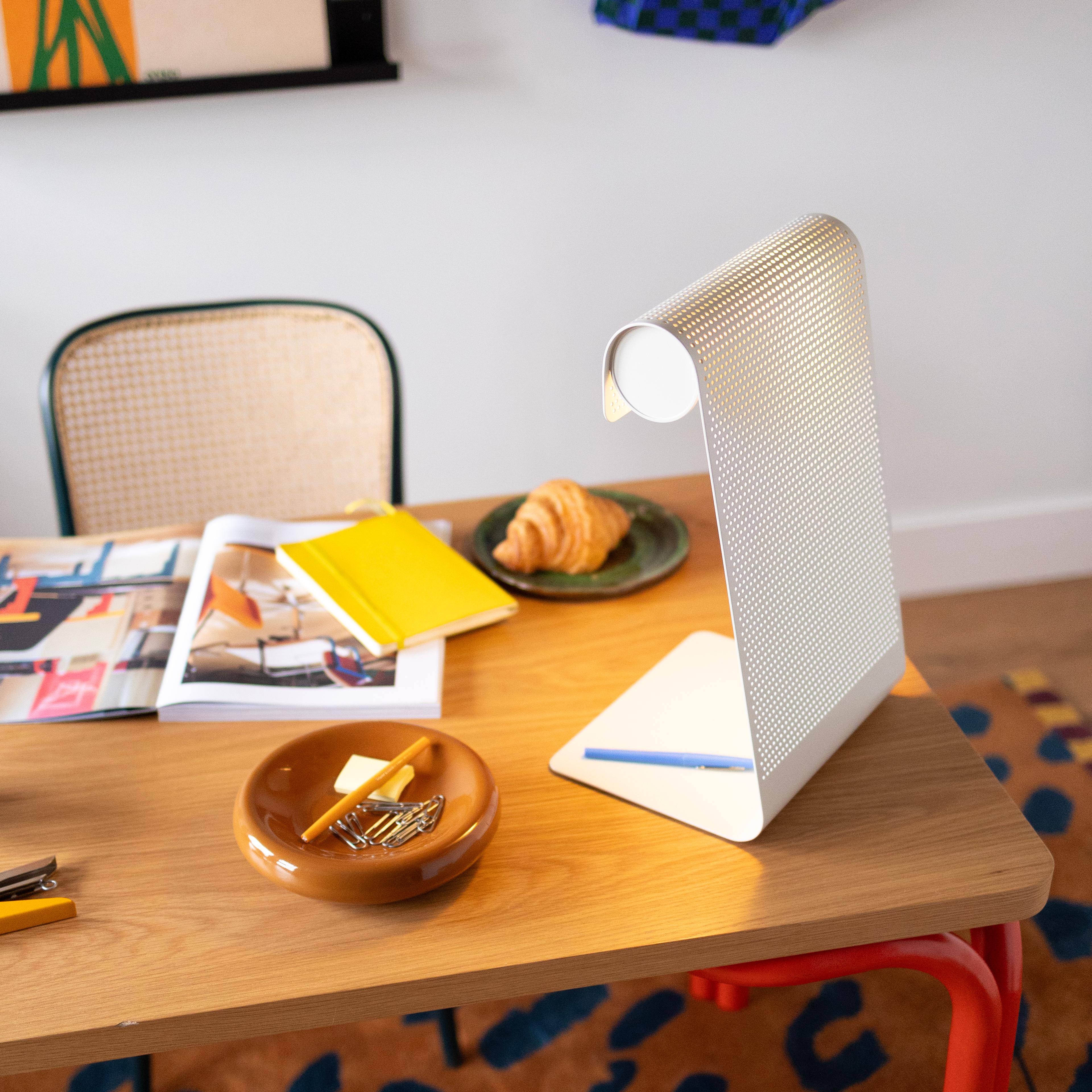 cobalt perforated task lamp on wooden cabinet next to butterscotch catchall