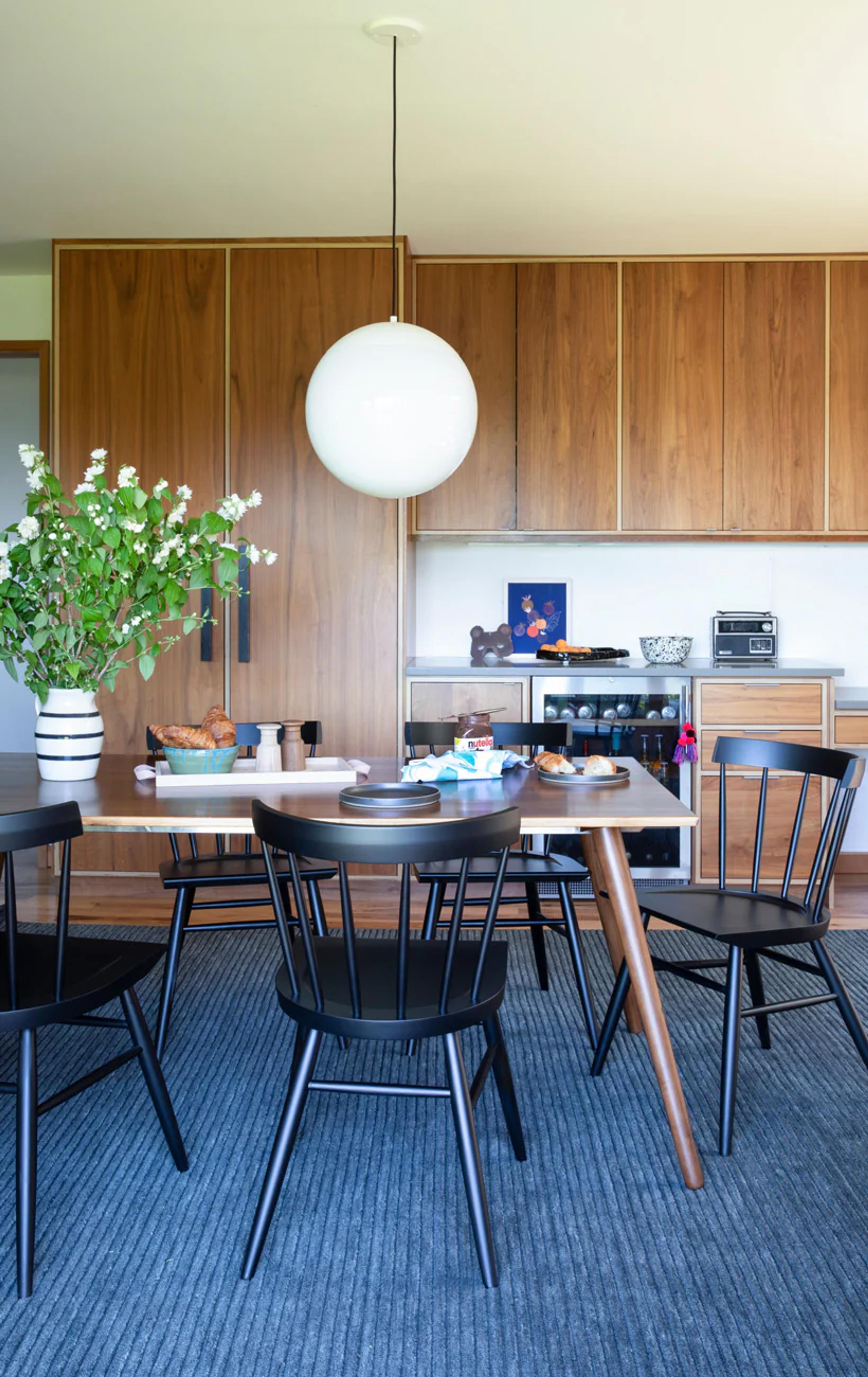 A dining room with black wooden chairs and an orb light chandelier