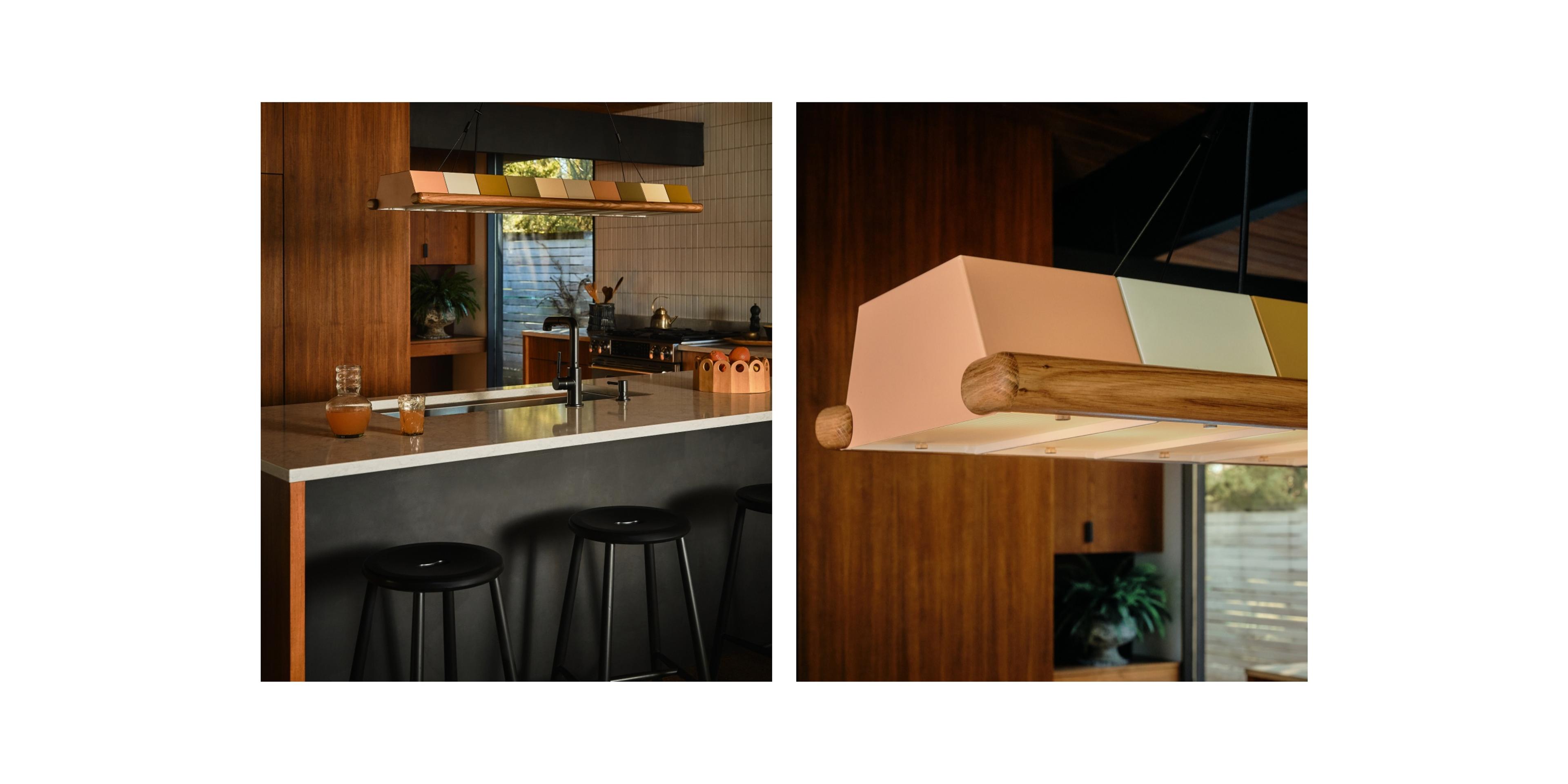 Low-lit kitchen island with metal multi-colored chandelier over deep metal sink