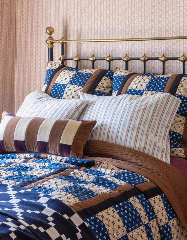 Maximalist bed with blue and cream quilt and shams