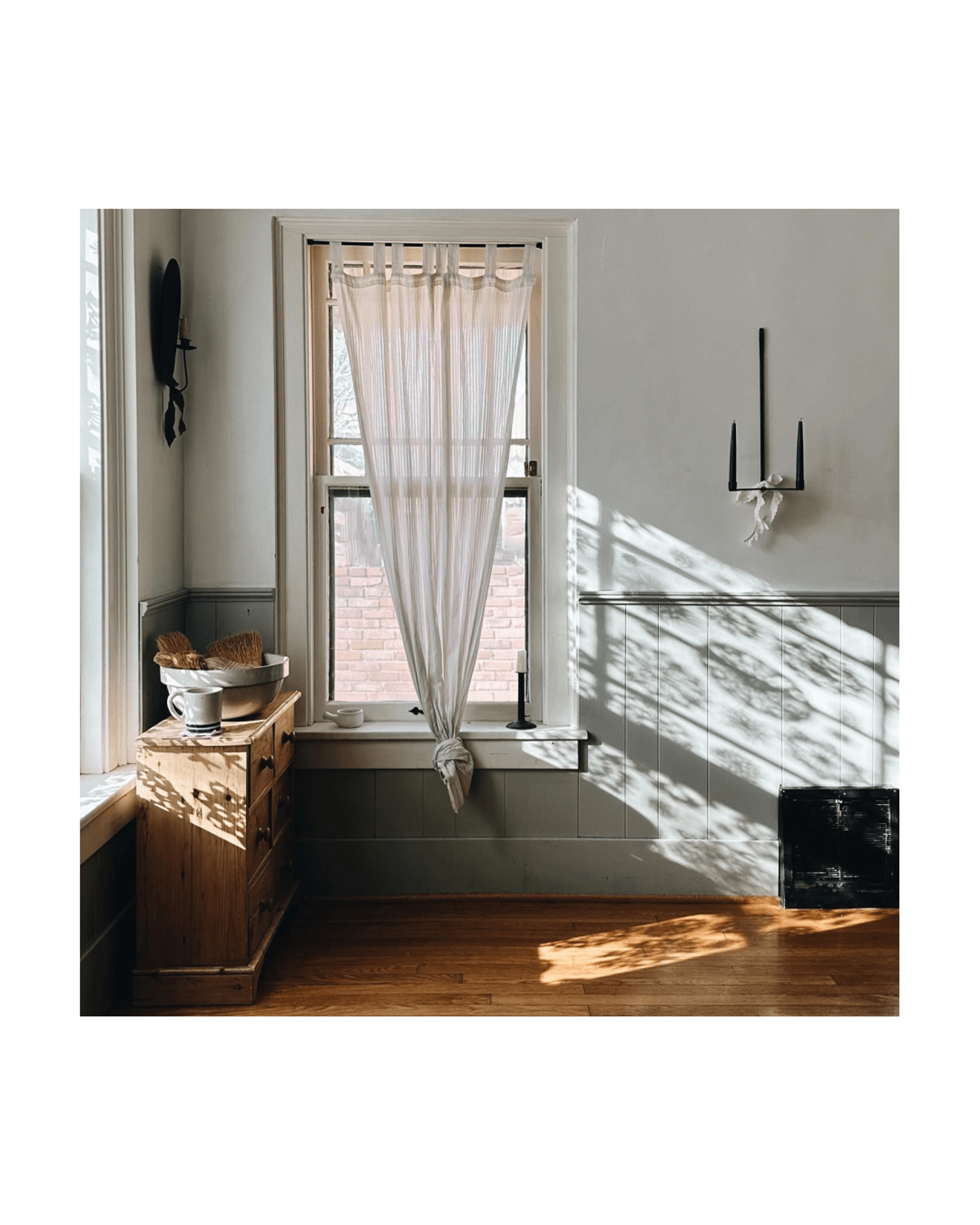 Livingroom window with wooden shutters and woven basket underneath