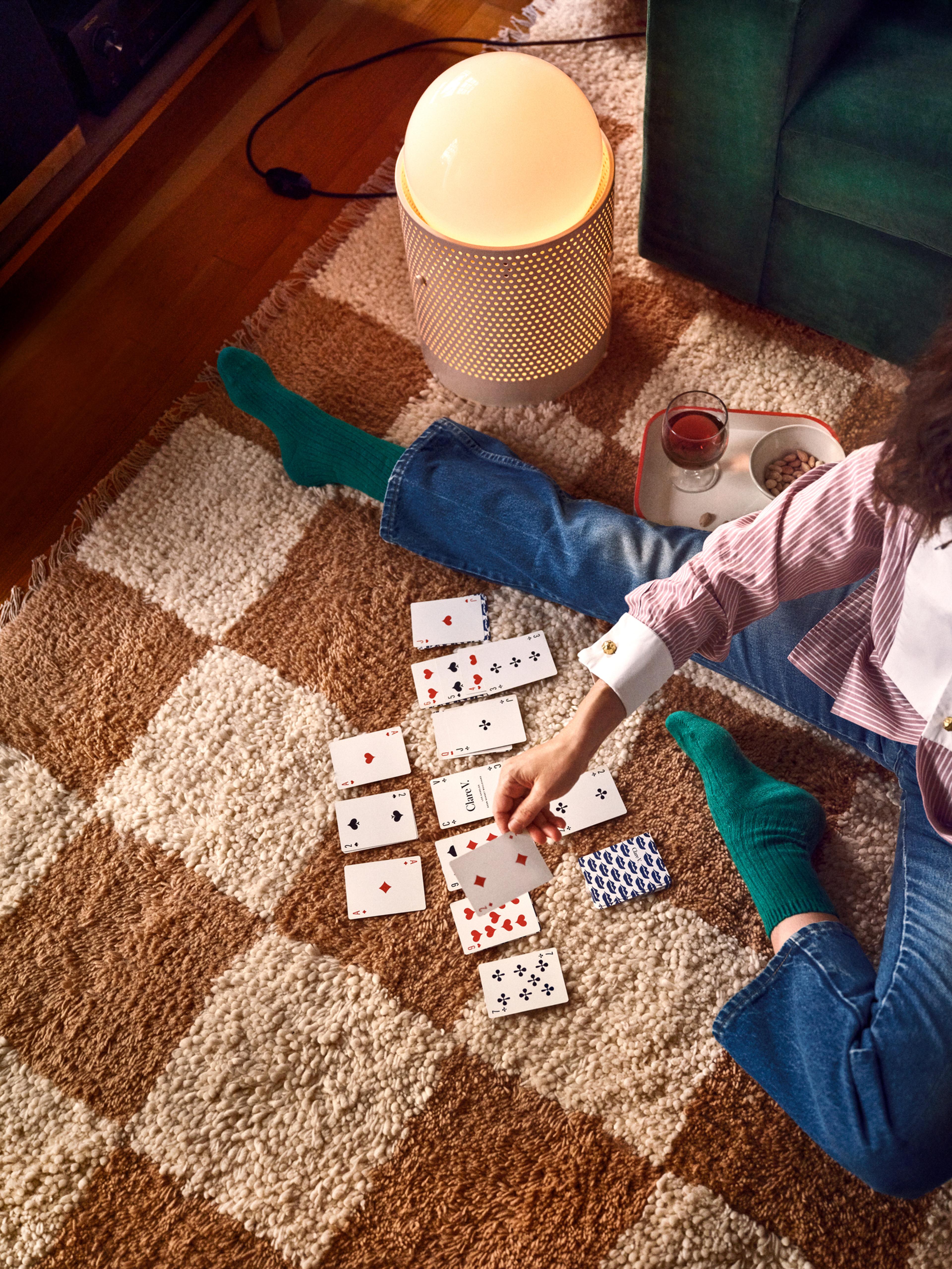 Person playing solitaire on the living room floor.
