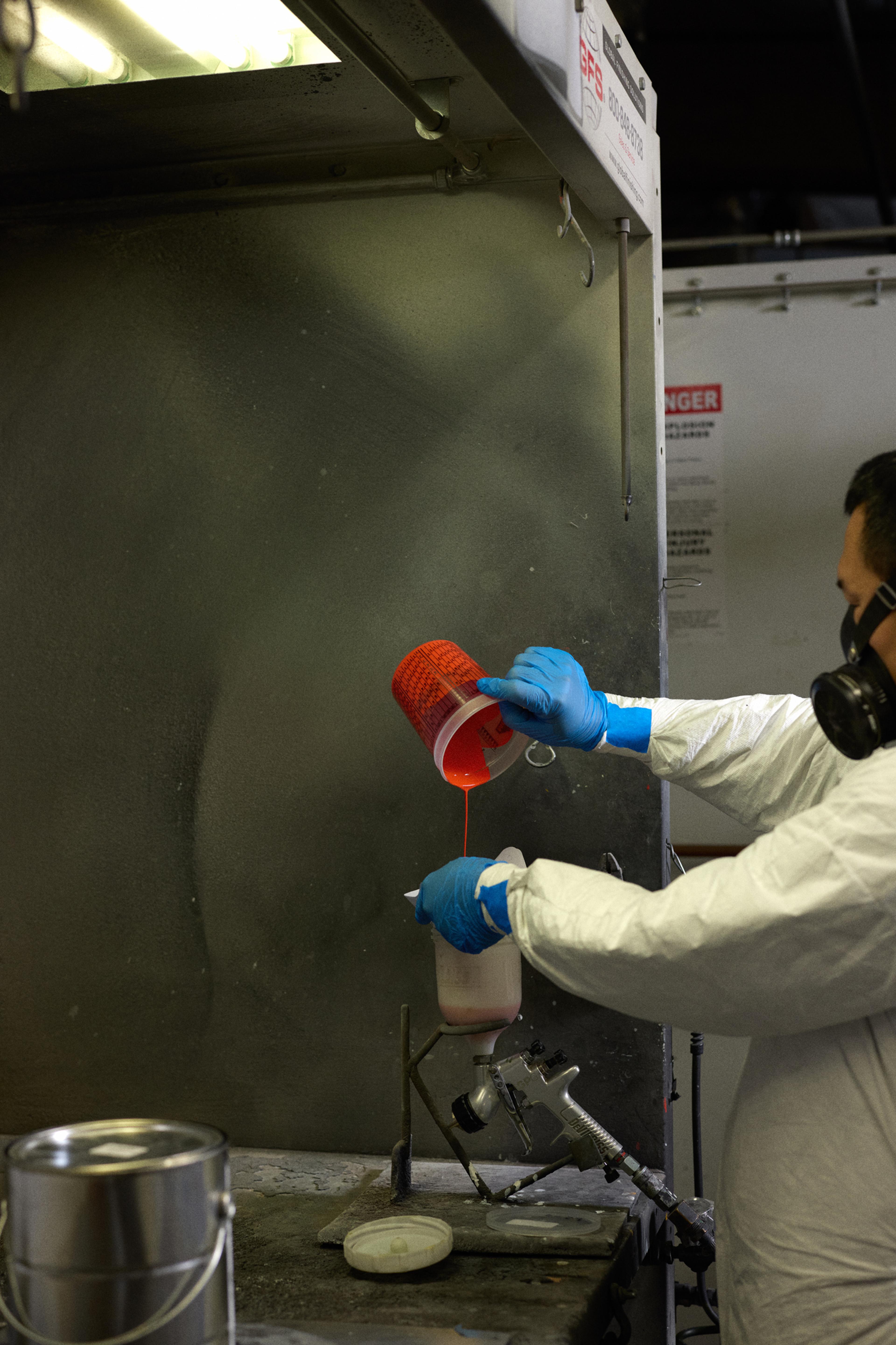 person pouring paint into spray gun