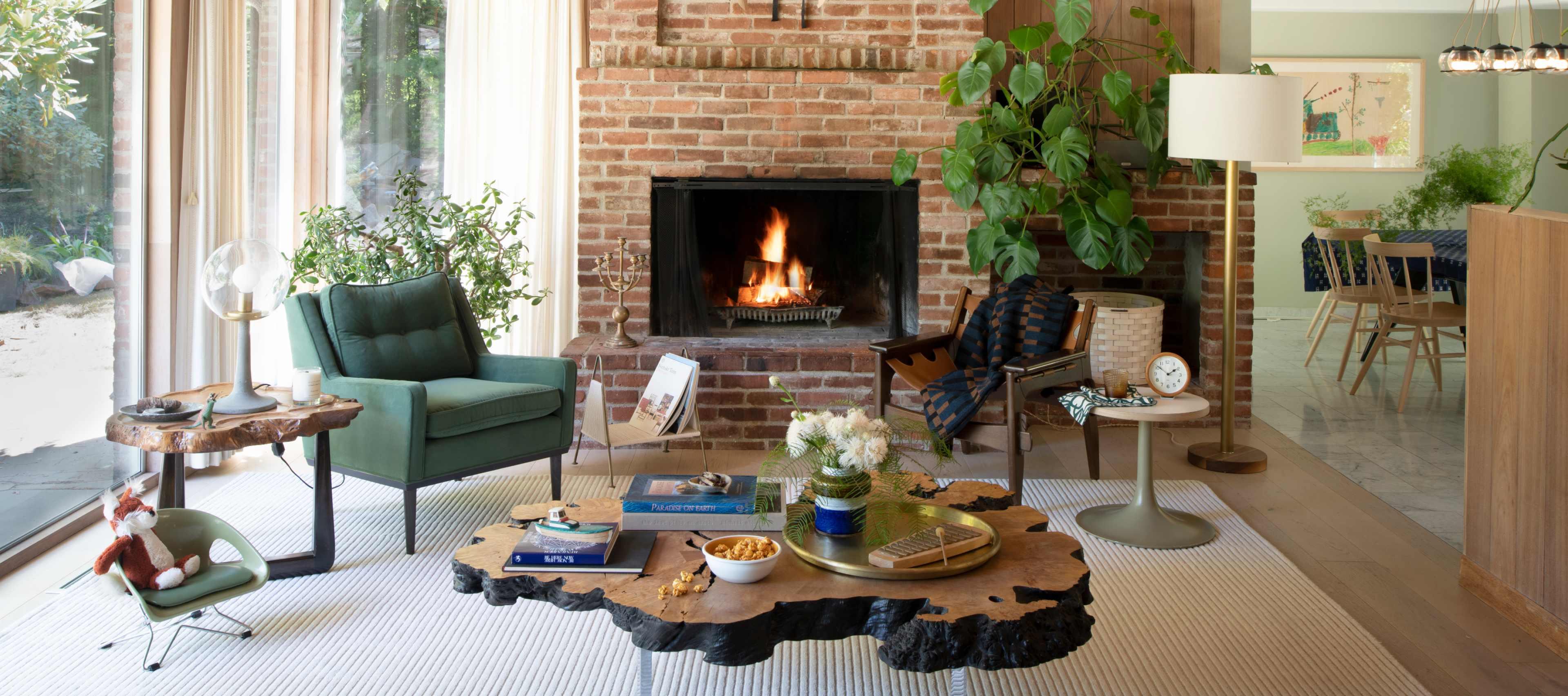 A light-filled living room with a green accent chair, wooden coffee table, and fireplace.