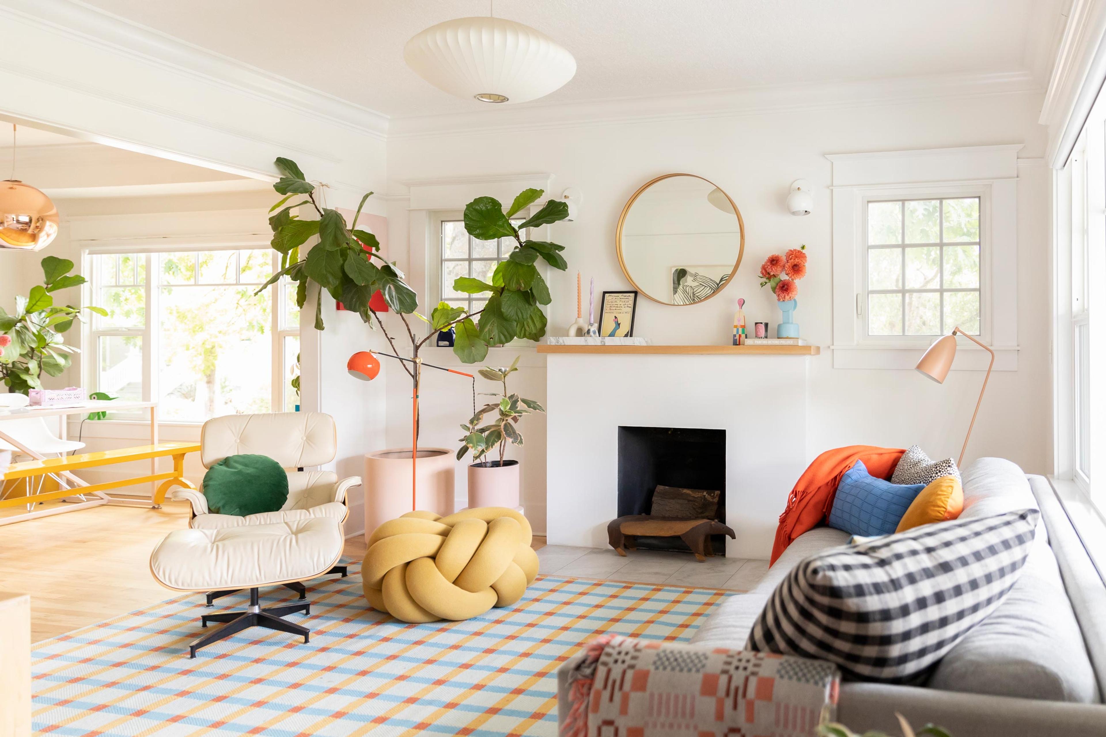 A light-filled, colorful living room with a fiddle leaf tree and a plaid rug.