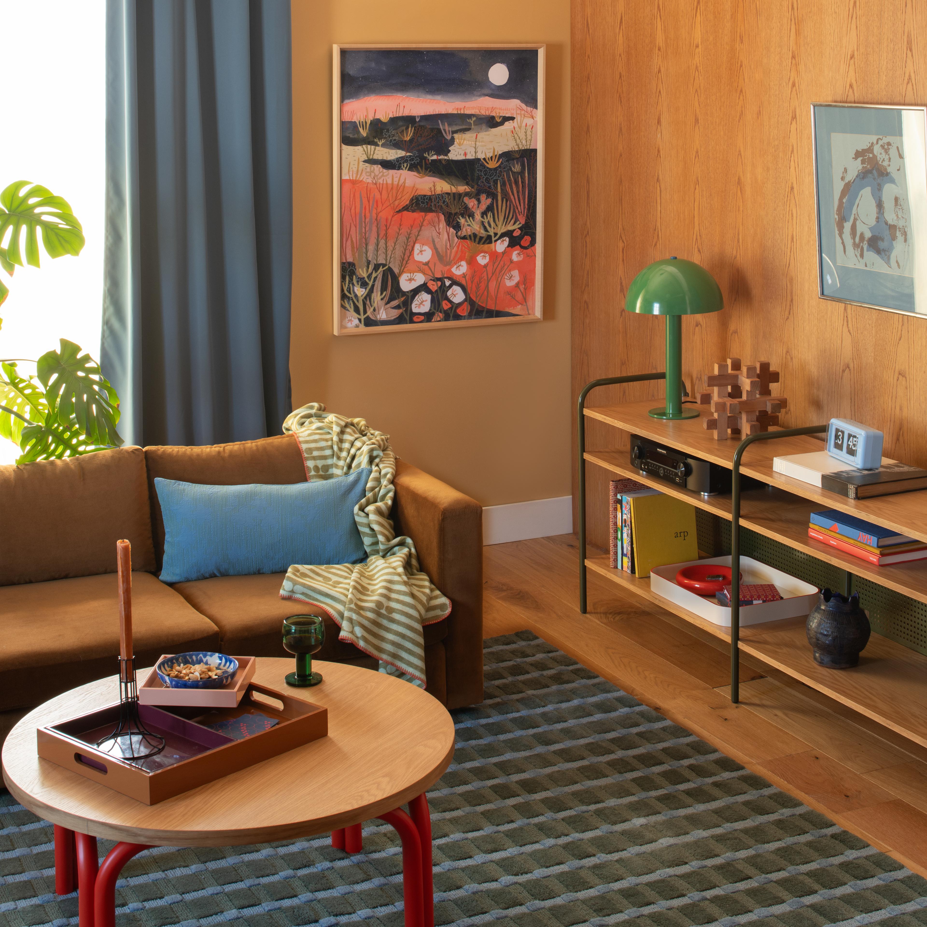 Colorful living room with wooden coffee table, velvet coffee couch and artist desert print hanging on wall
