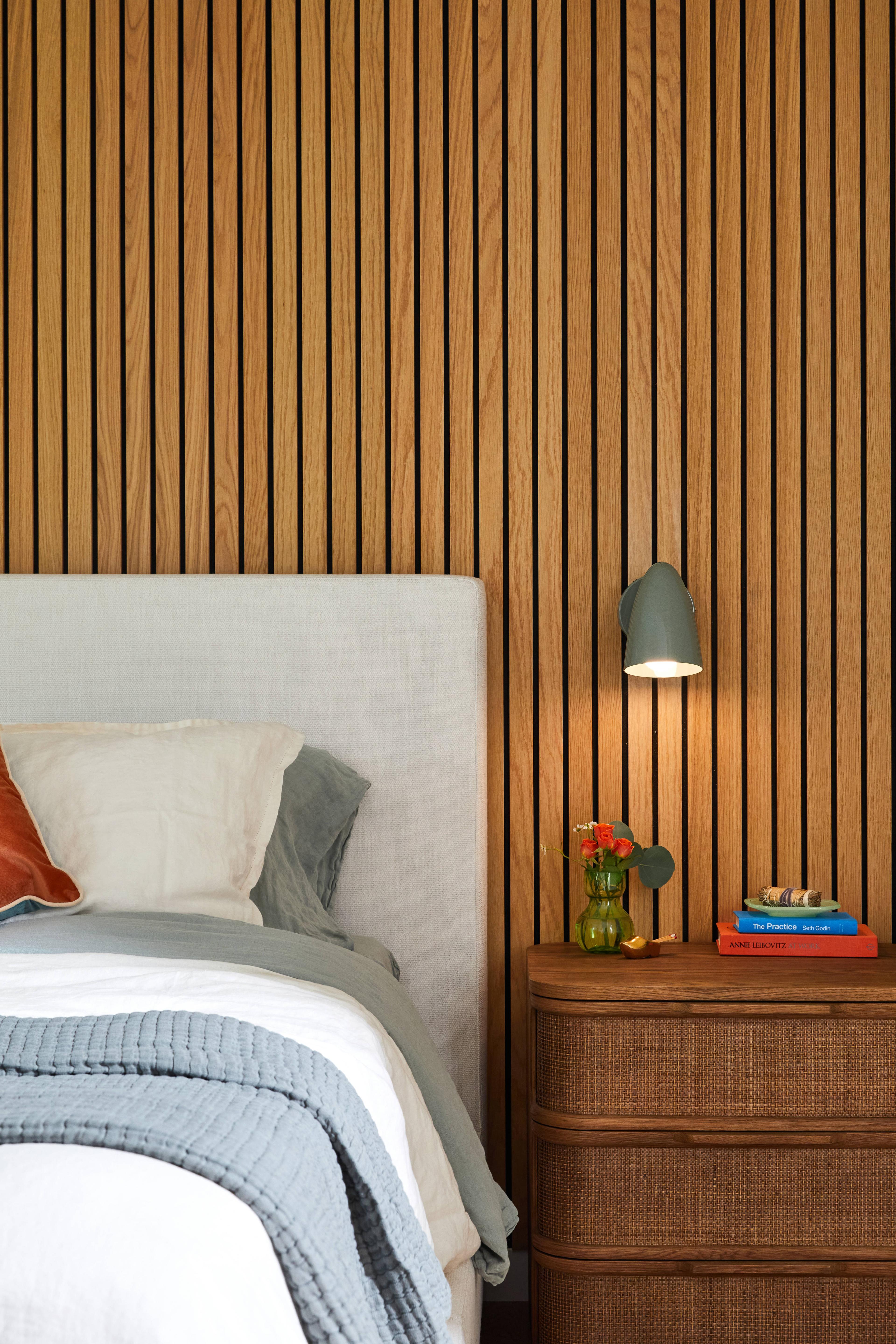 Cozy bedroom with slat wall behind bed. 