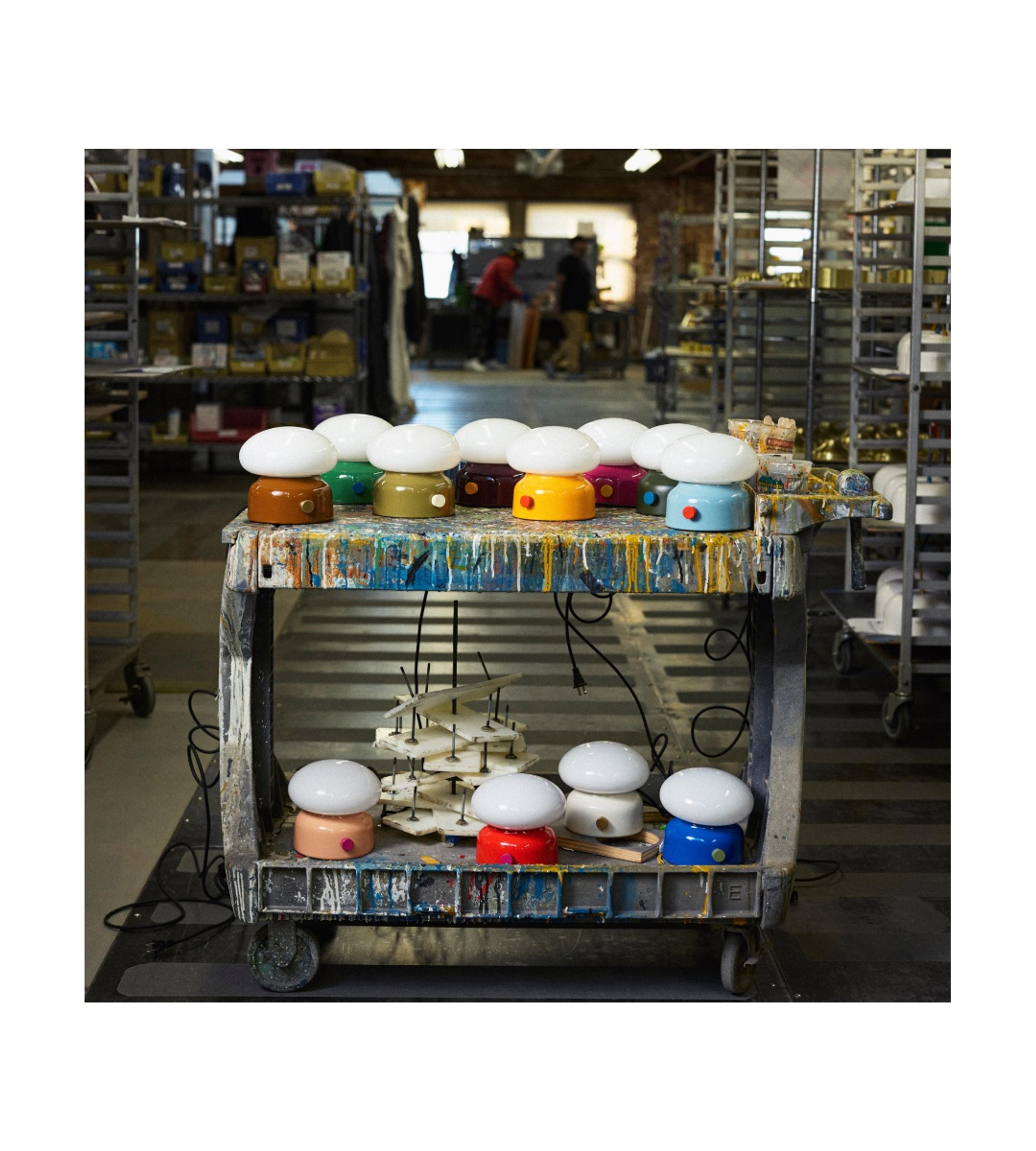 set of multi-colored table lamps on paint cart in middle of paint floor of factory