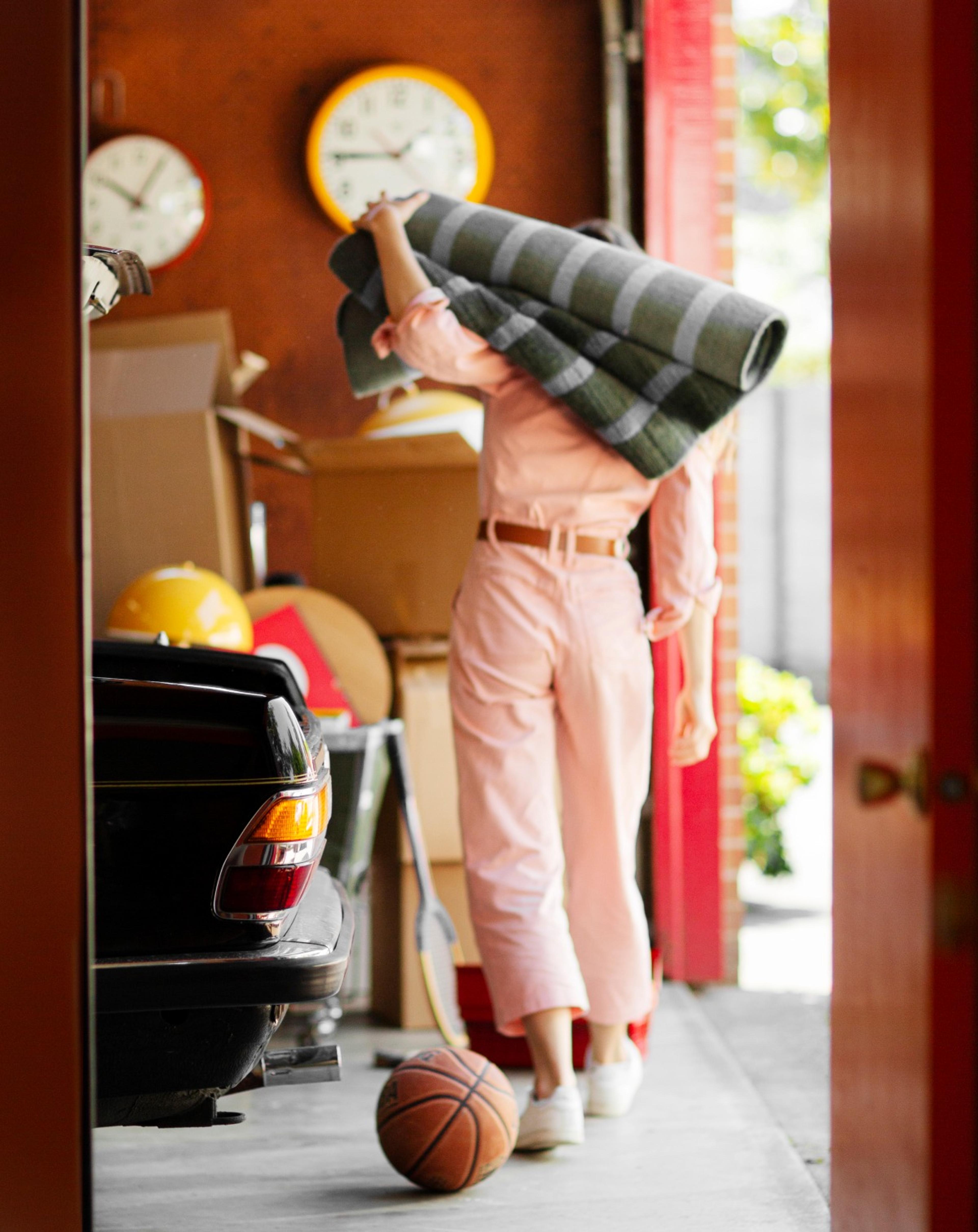 Woman carrying a rug in a cluttered garage