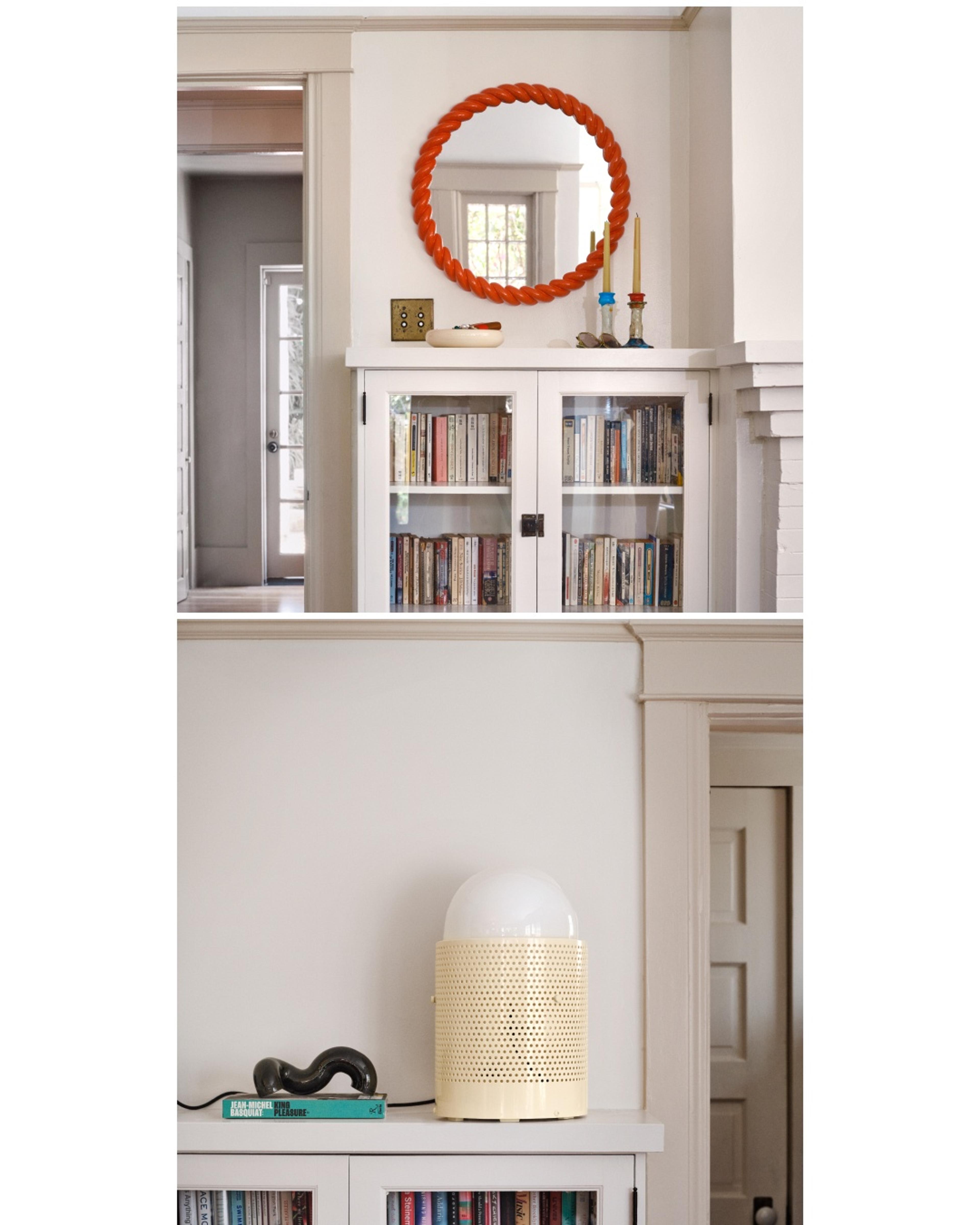 Built-in bookcases with modern lamp and red mirror.