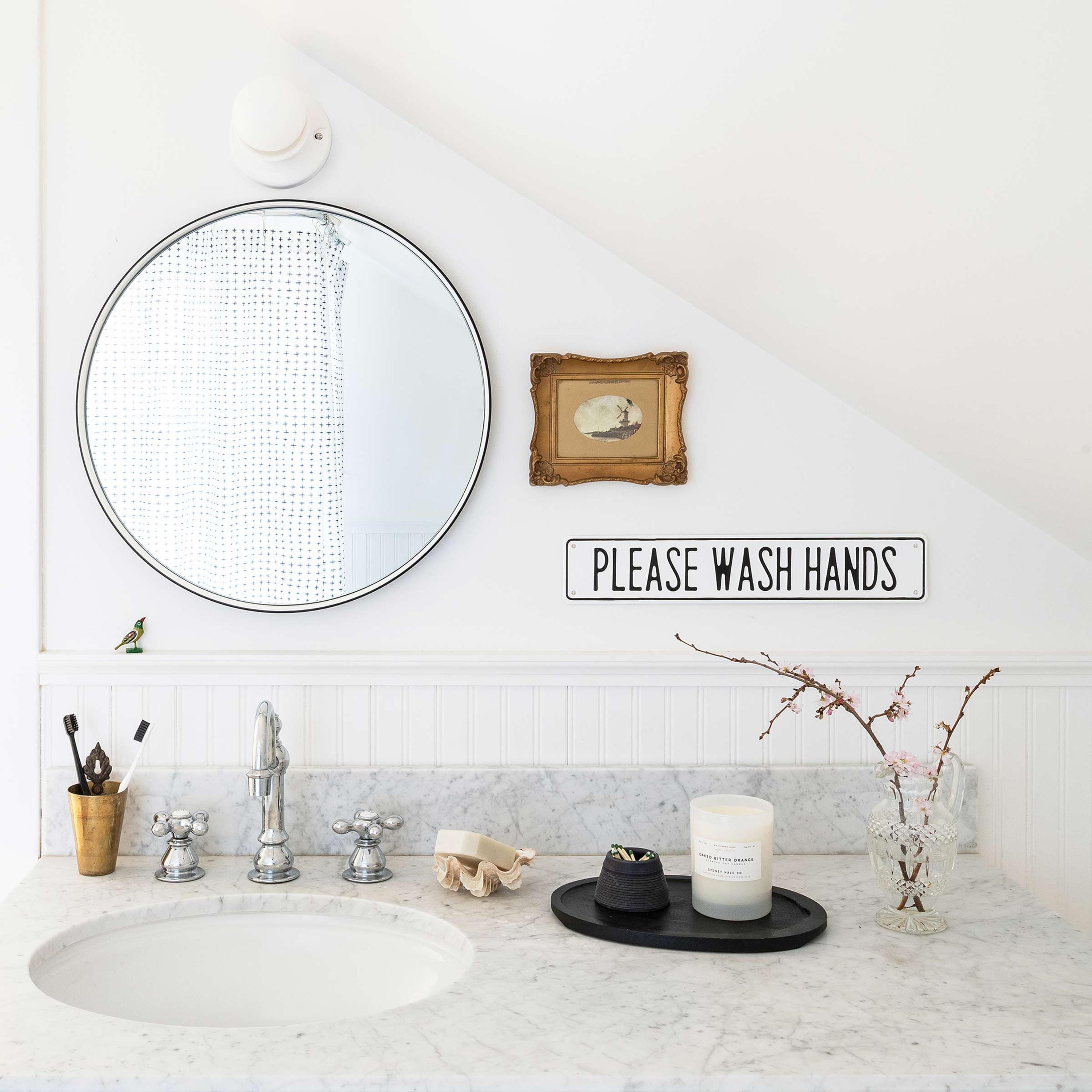 A small bathroom with a round mirror.