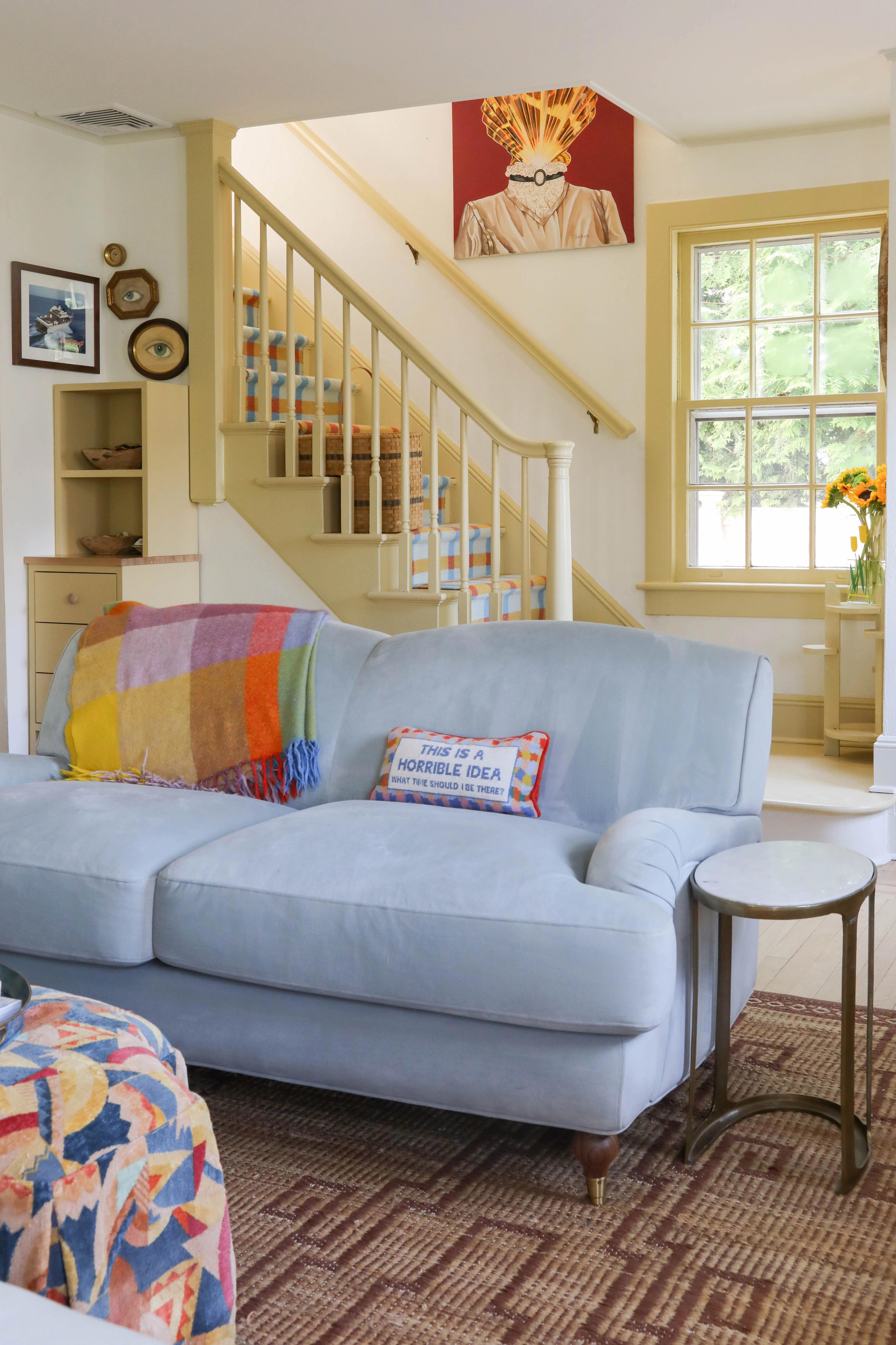 Fun family/ living room, blue sofa with colorful pillows and light yellow walls.