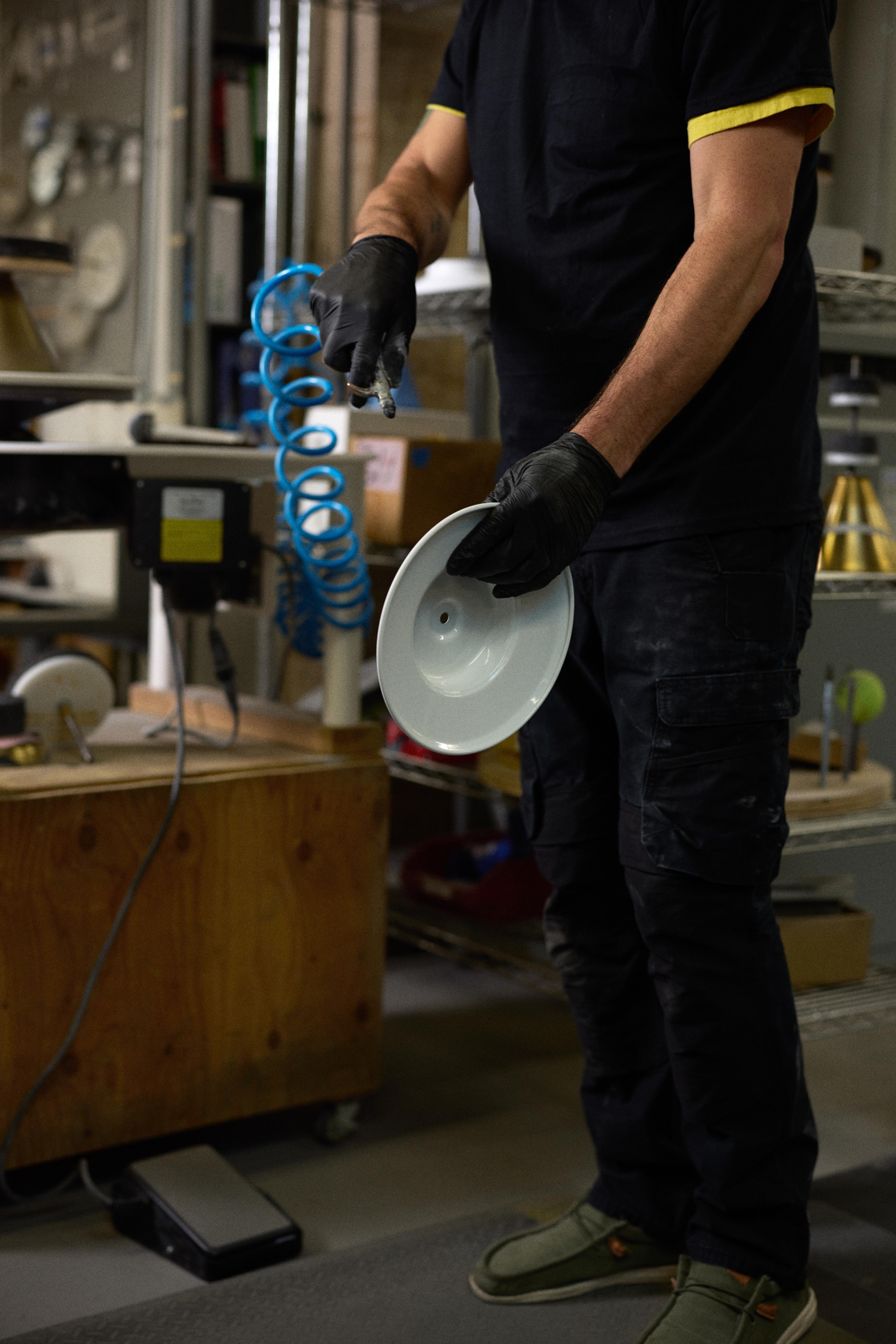 person blowing off dust from sanding of light shade