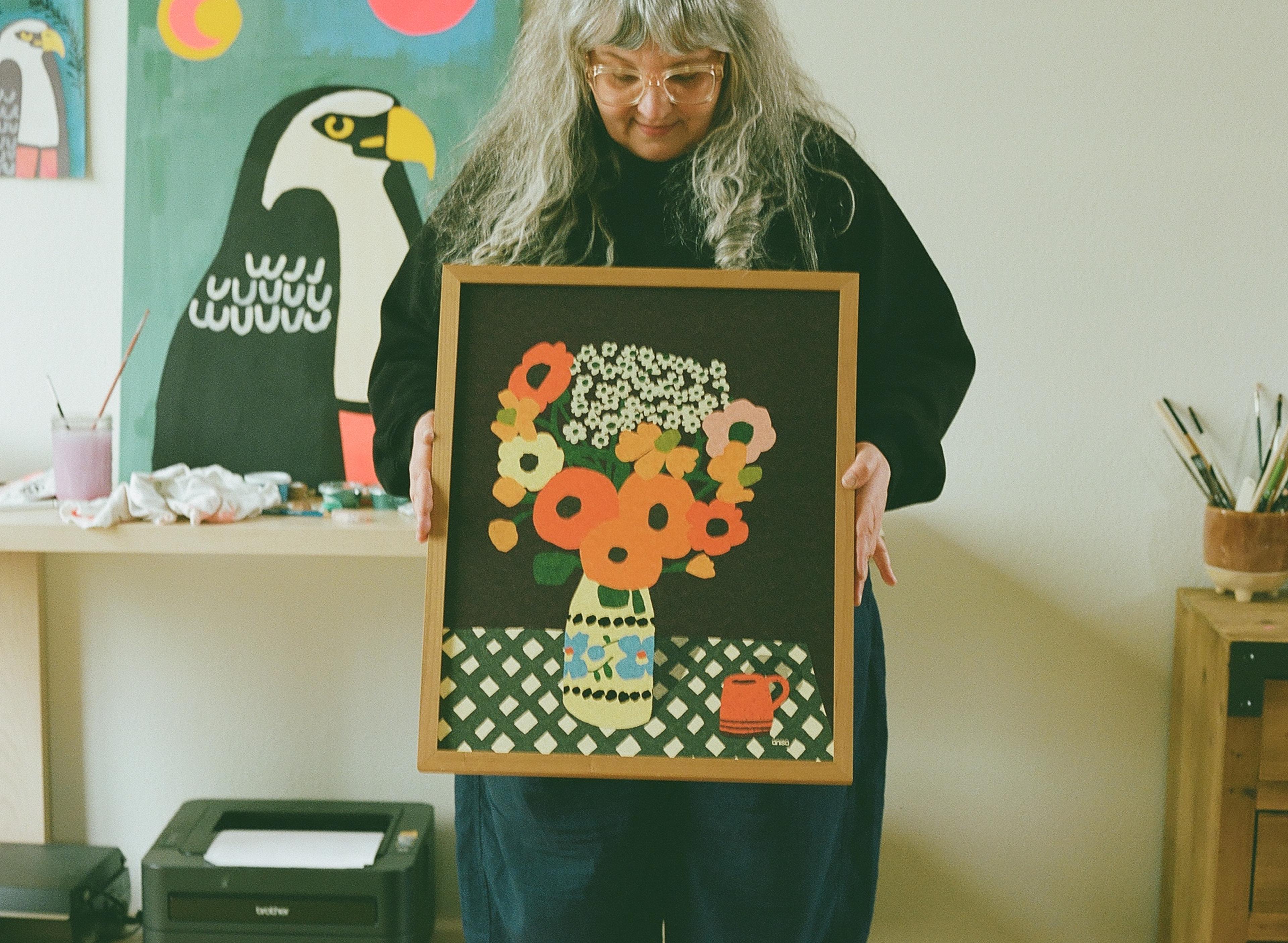 Artist holding print with vase and flowers