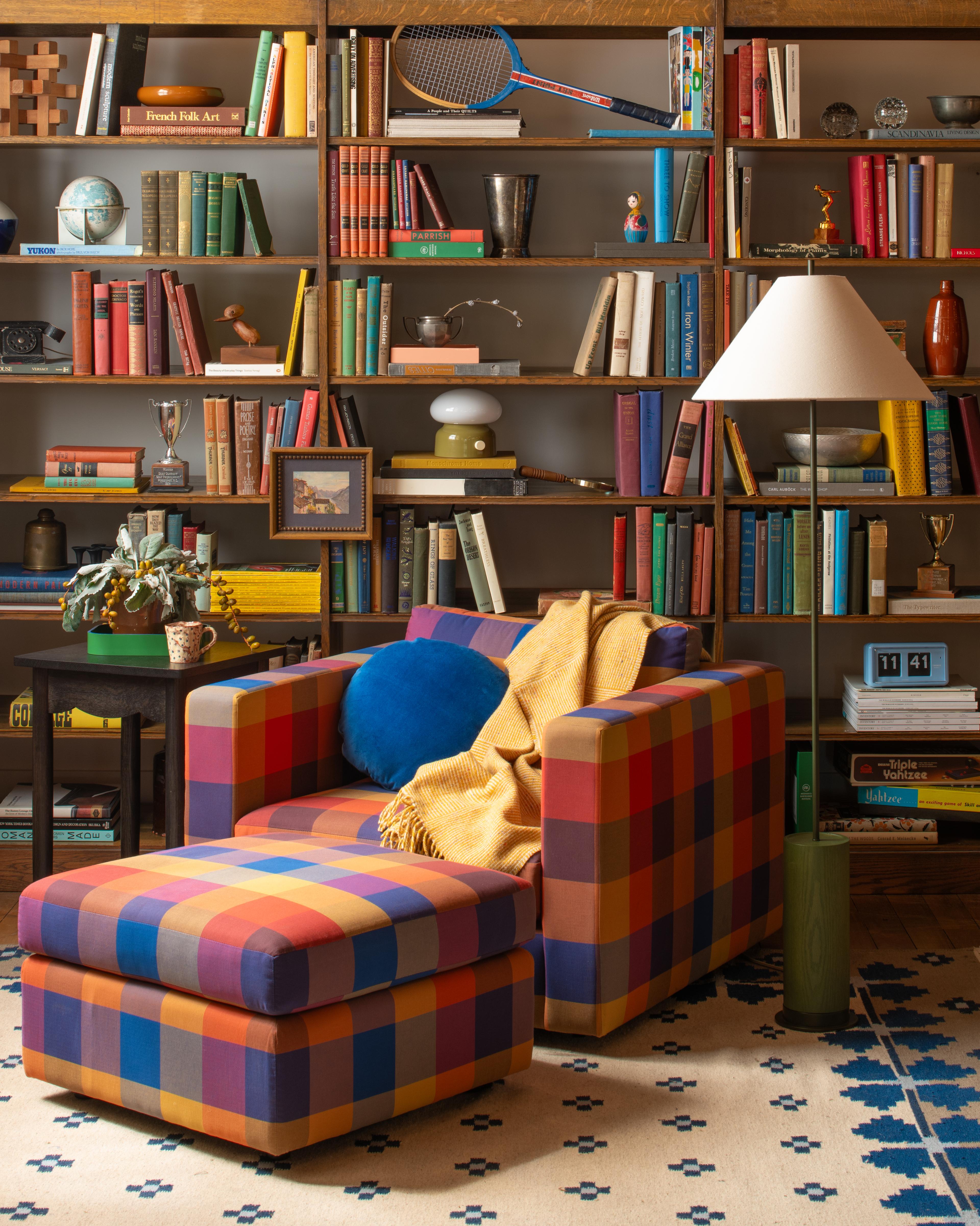 Plaid chair in front of maximalist bookshelf