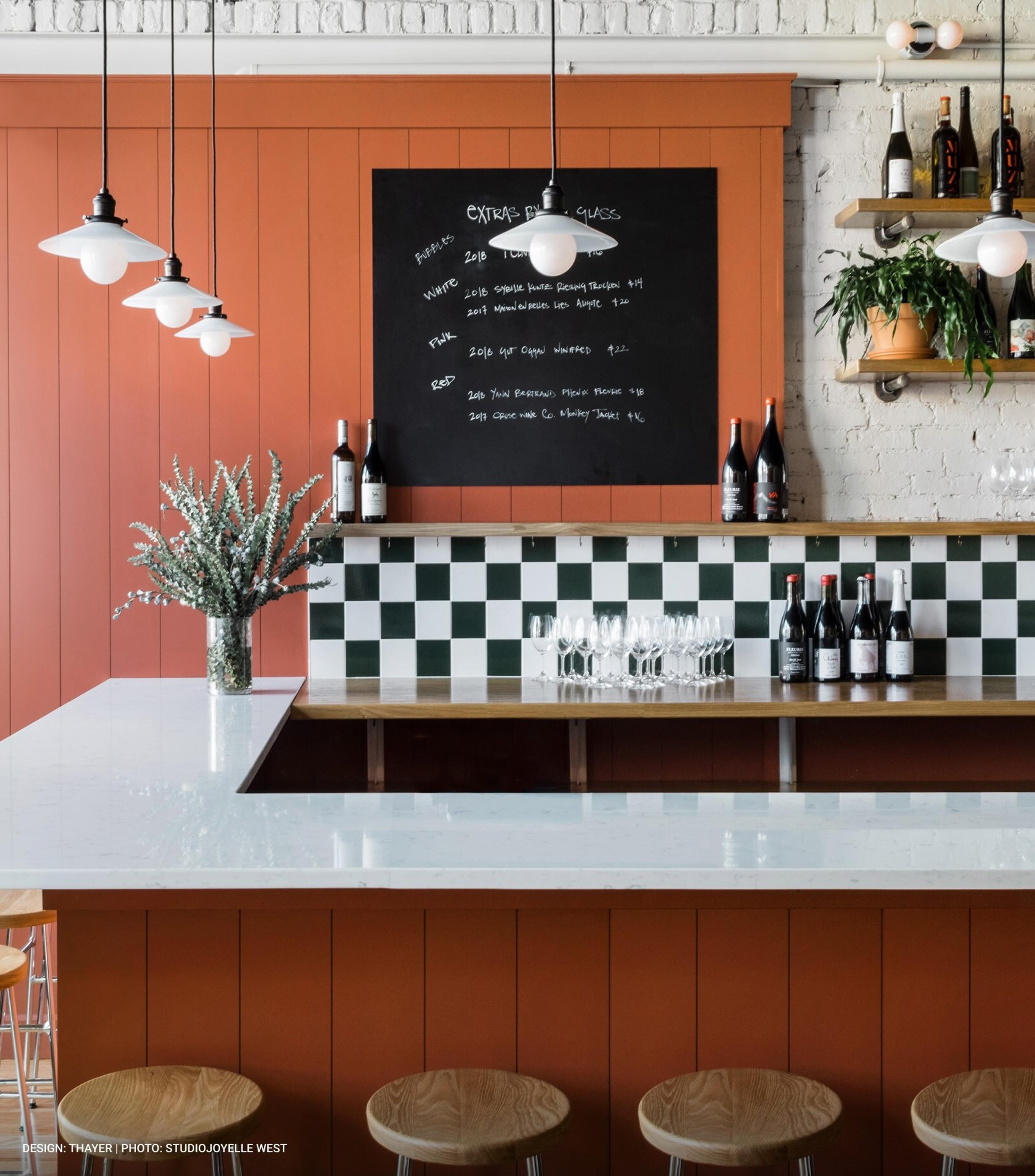 Wall covered in writing and post it notes, black chair and white table in foreground