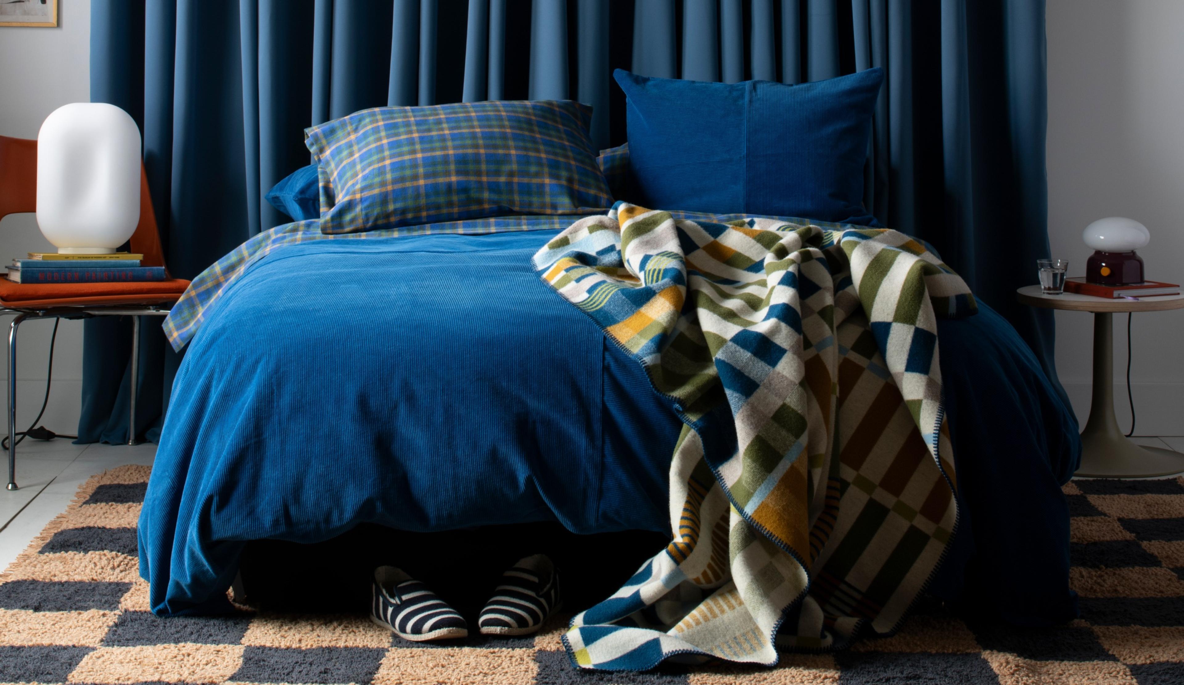 queen bed with cobalt and plaid bedding