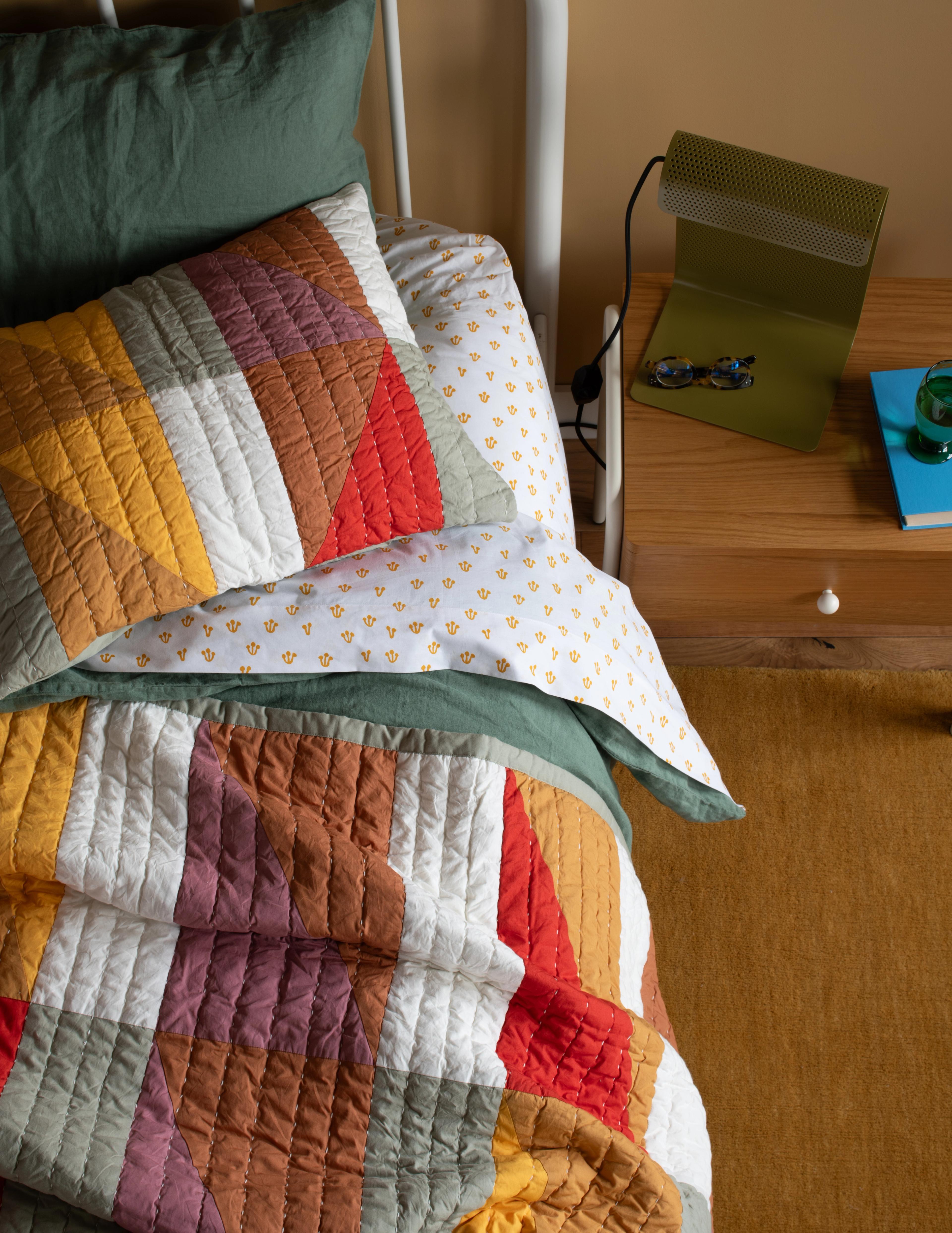 bedding stack with colorful sheets and quilt