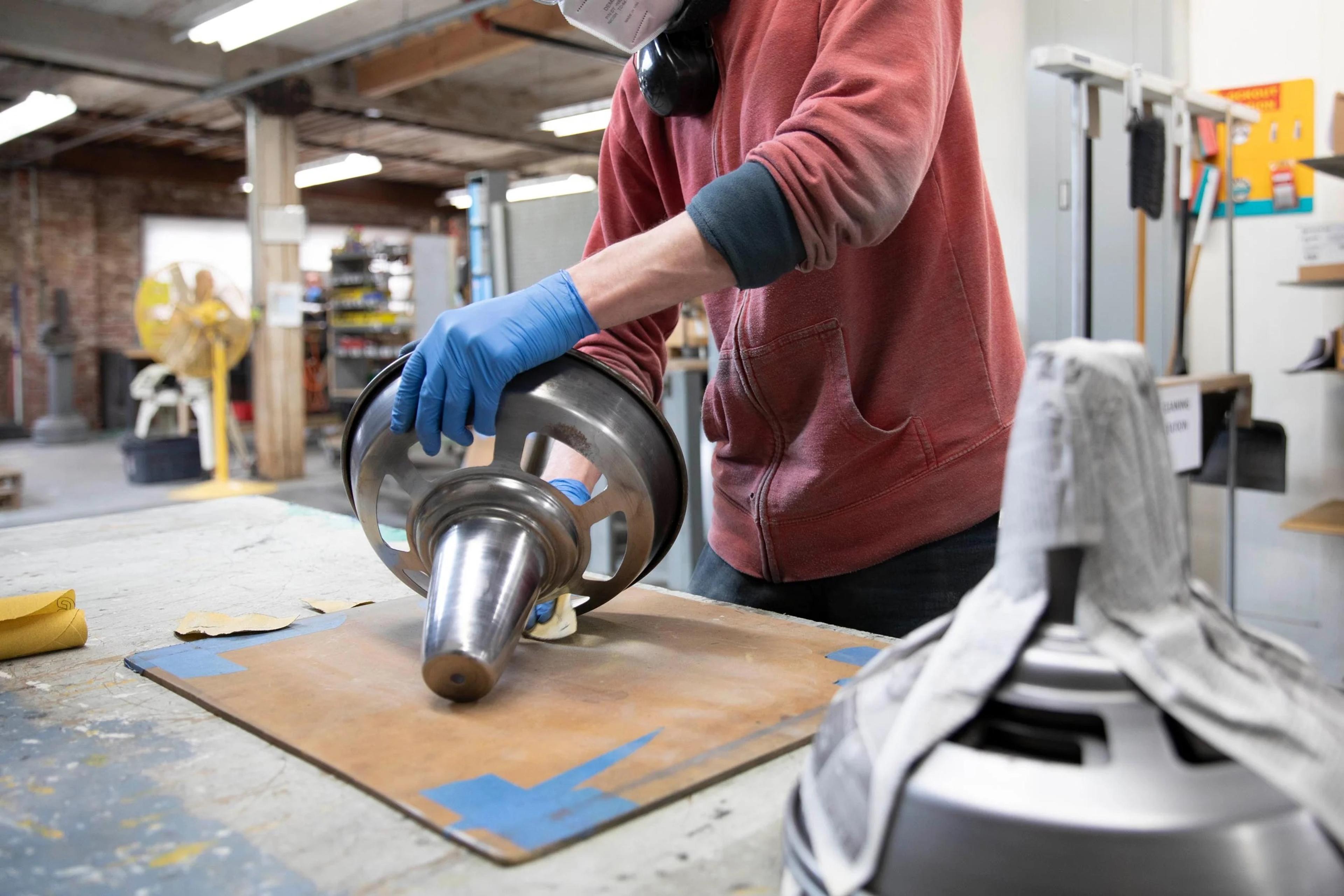 Factory worker sanding metal shade to be painted